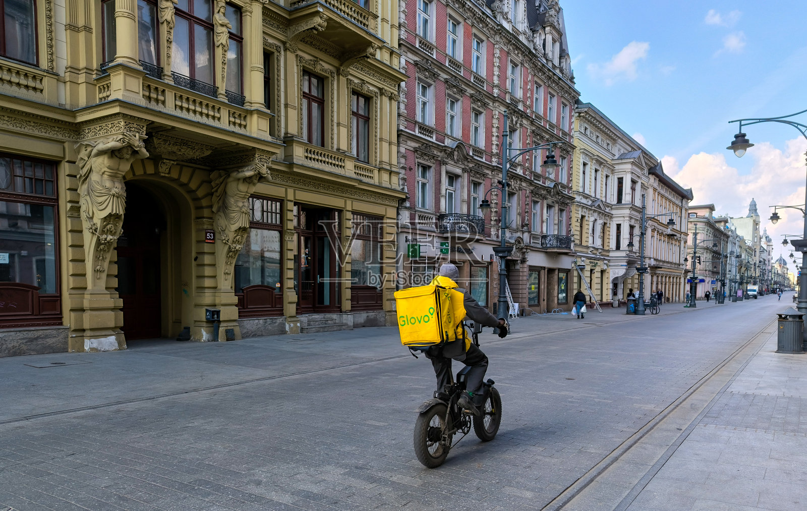 波兰罗兹 - 2025年12月03日:来自Glovo公司的食品和餐品配送员在罗兹街头。照片摄影图片