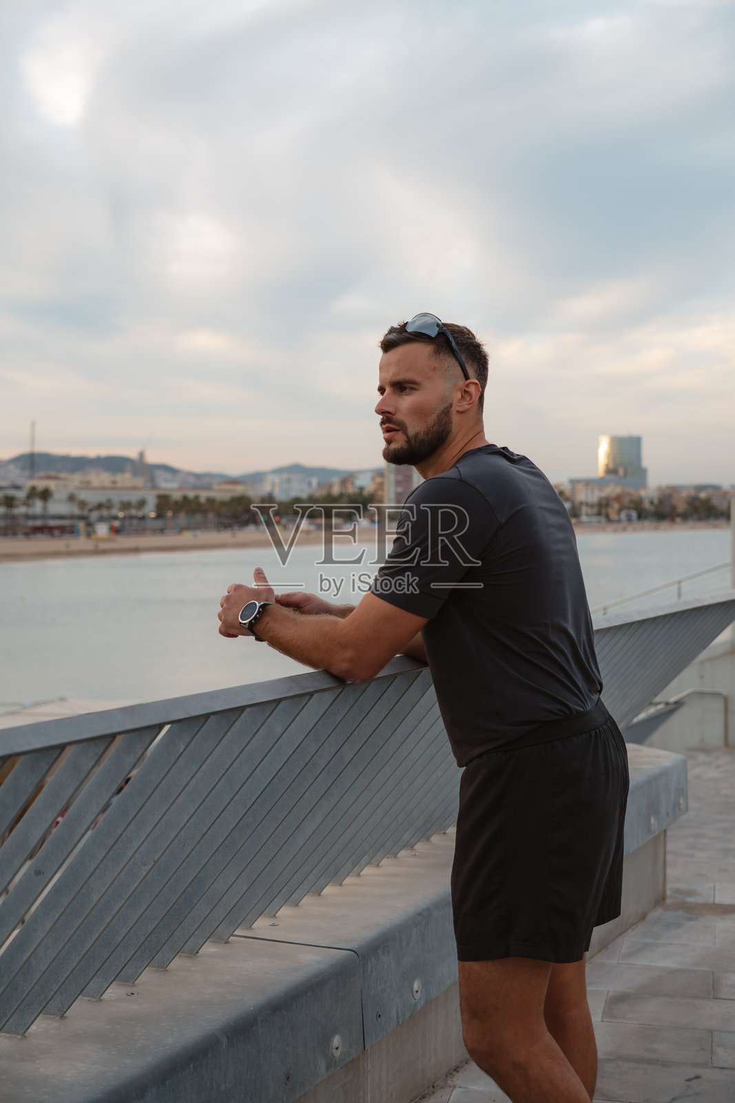 运动员在训练后休息，欣赏巴塞罗那的海滨景色照片摄影图片
