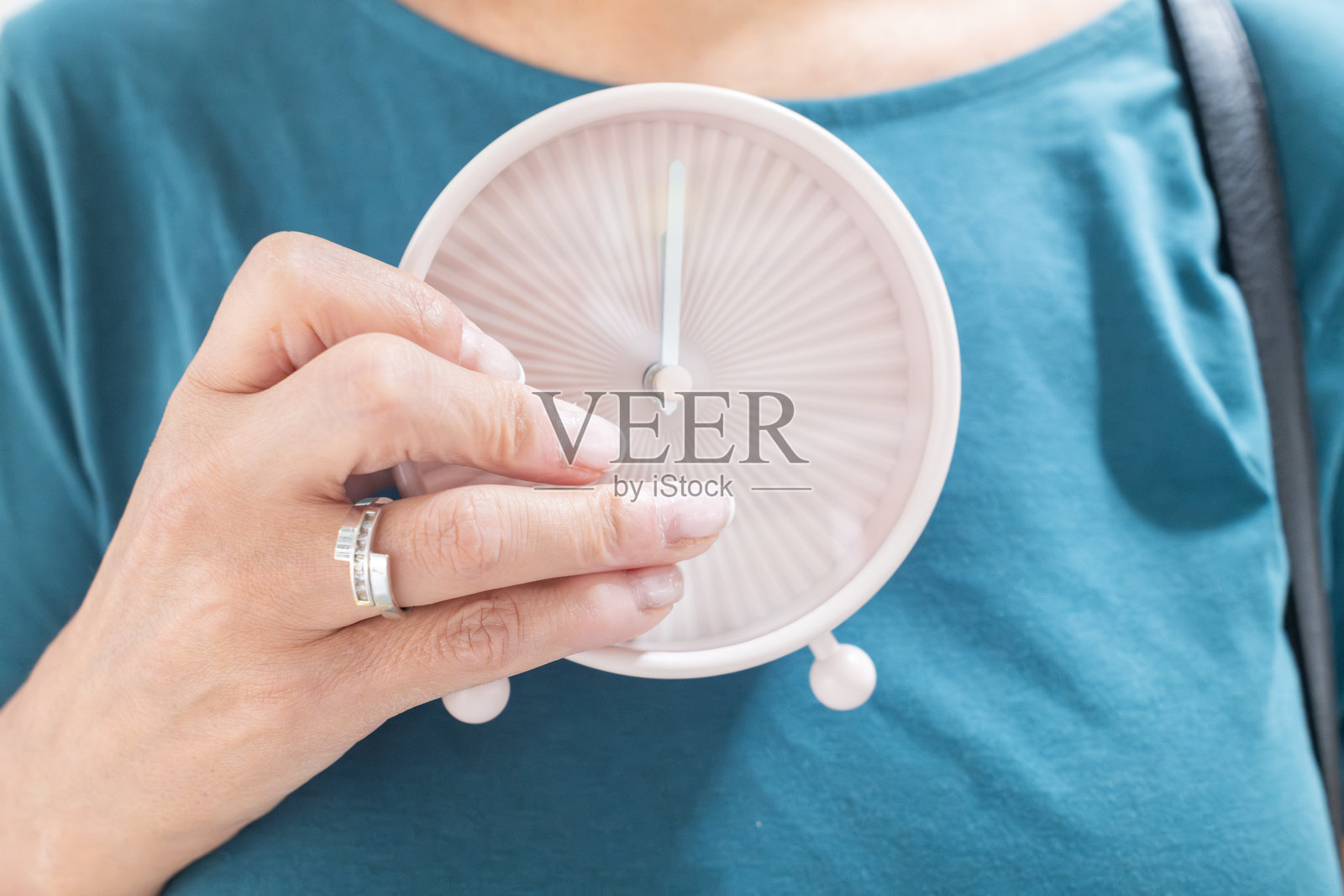 无法辨认的女性手持显示十二点的时钟照片摄影图片