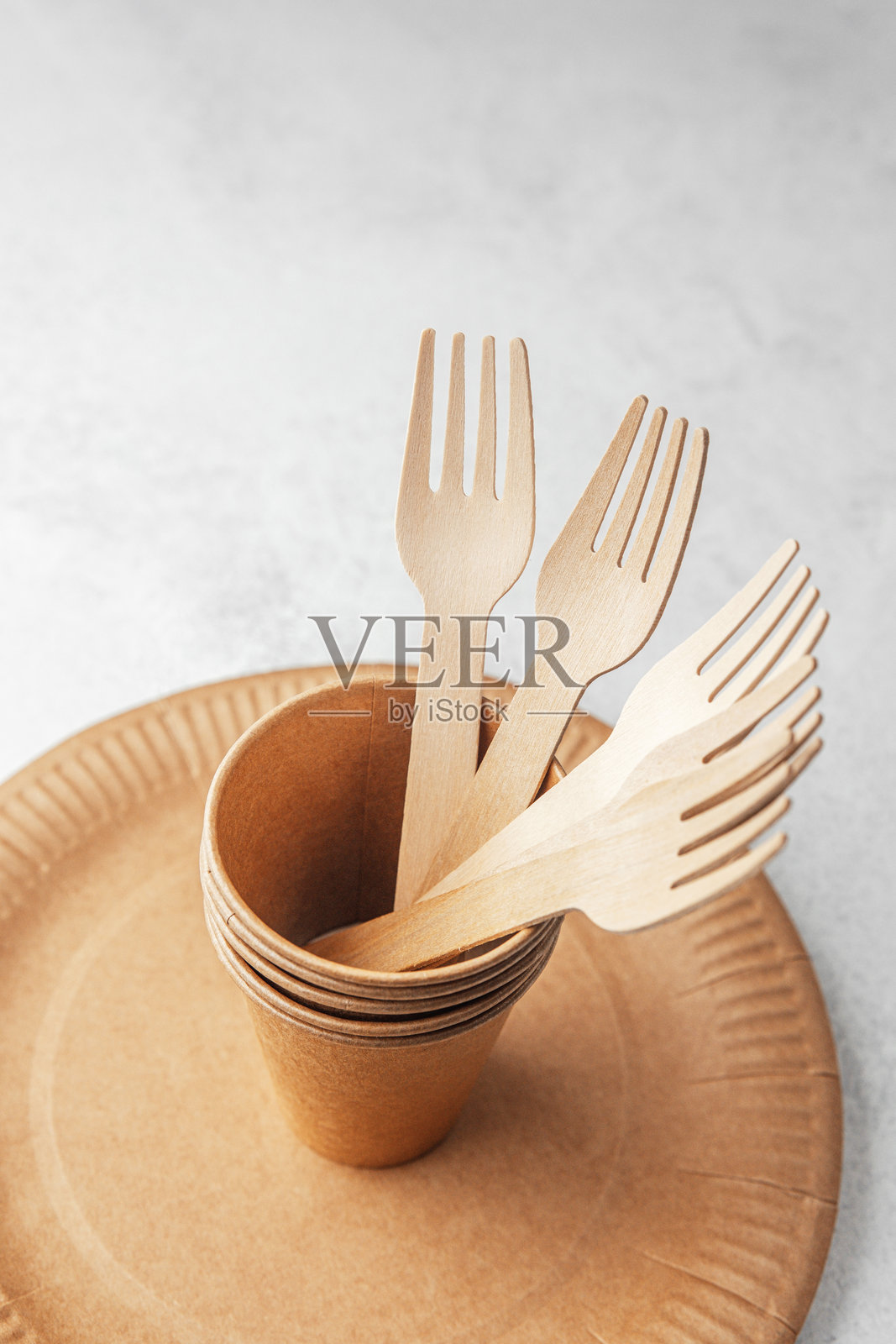 环保纸杯与木制叉子放在一次性盘子上，背景为白色。照片摄影图片