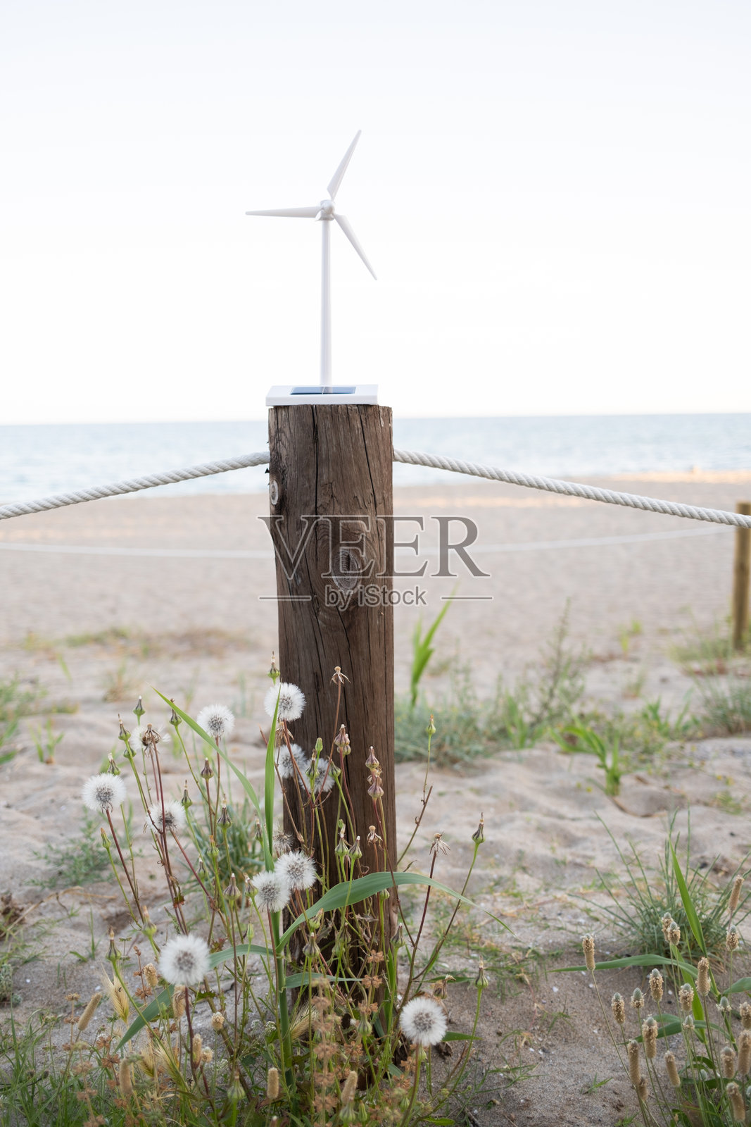 海滩上木桩上的迷你风力发电机和太阳能板照片摄影图片