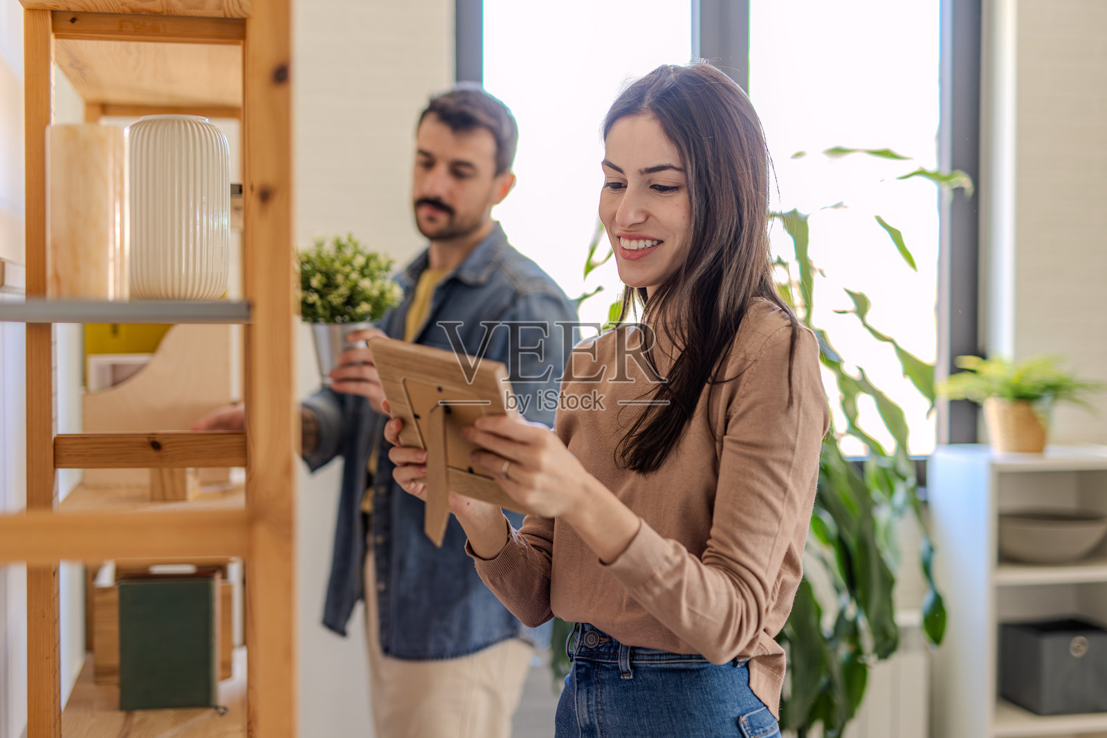 年轻情侣在装饰他们的新公寓，把相框放在架子上照片摄影图片