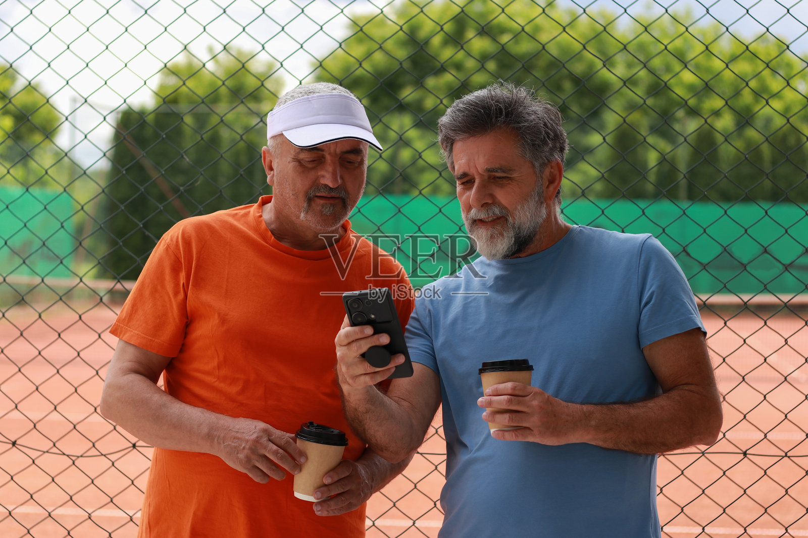 两位老年男性在训练前享受咖啡和交谈。照片摄影图片