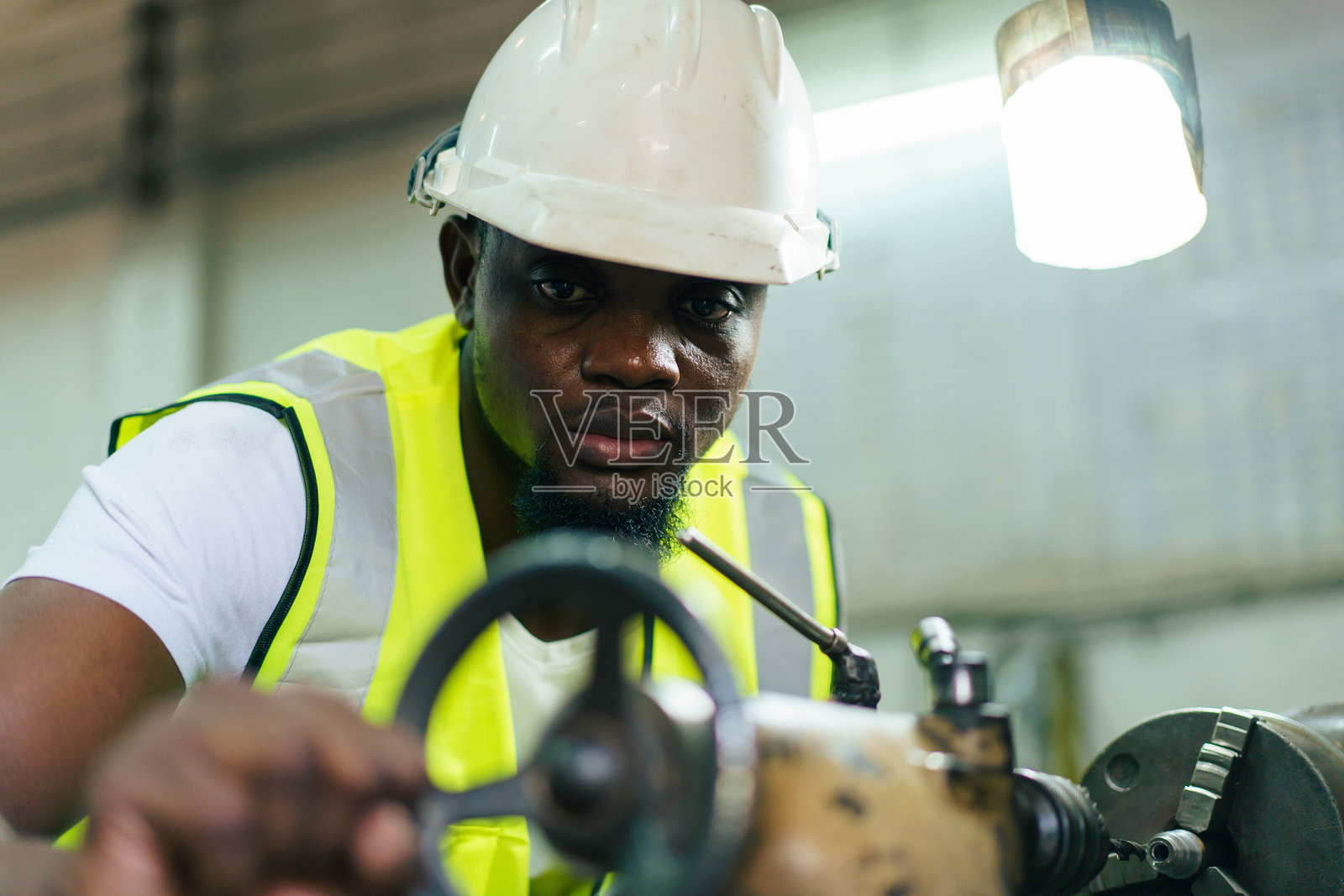 美国非洲裔男性工程师在工厂进行机器的检查和修理。照片摄影图片