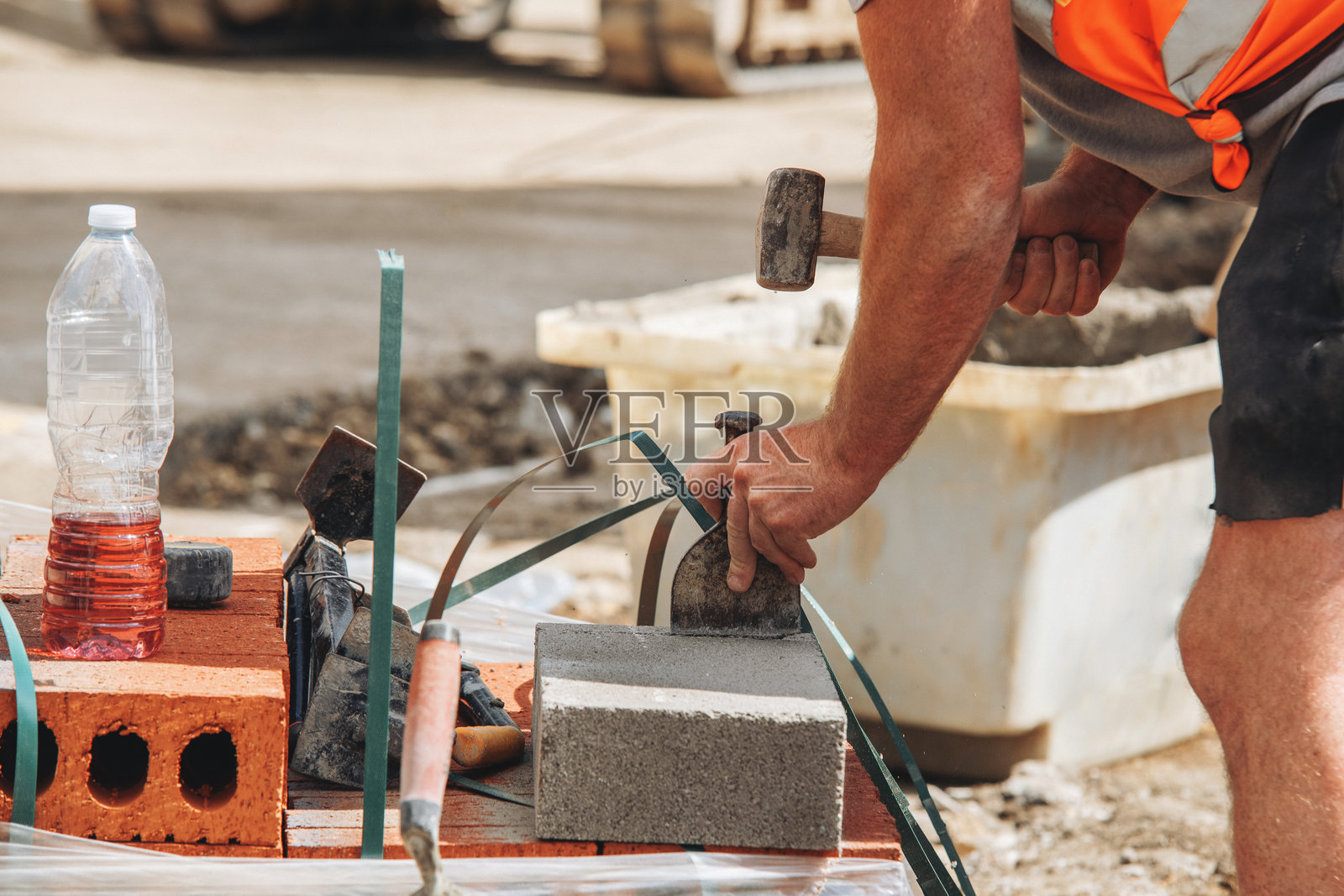 工人在住宅楼的梁和块地面施工中，用凿子和锤子将混凝土块切割成合适的尺寸，以便将其放置在混凝土梁之间。照片摄影图片