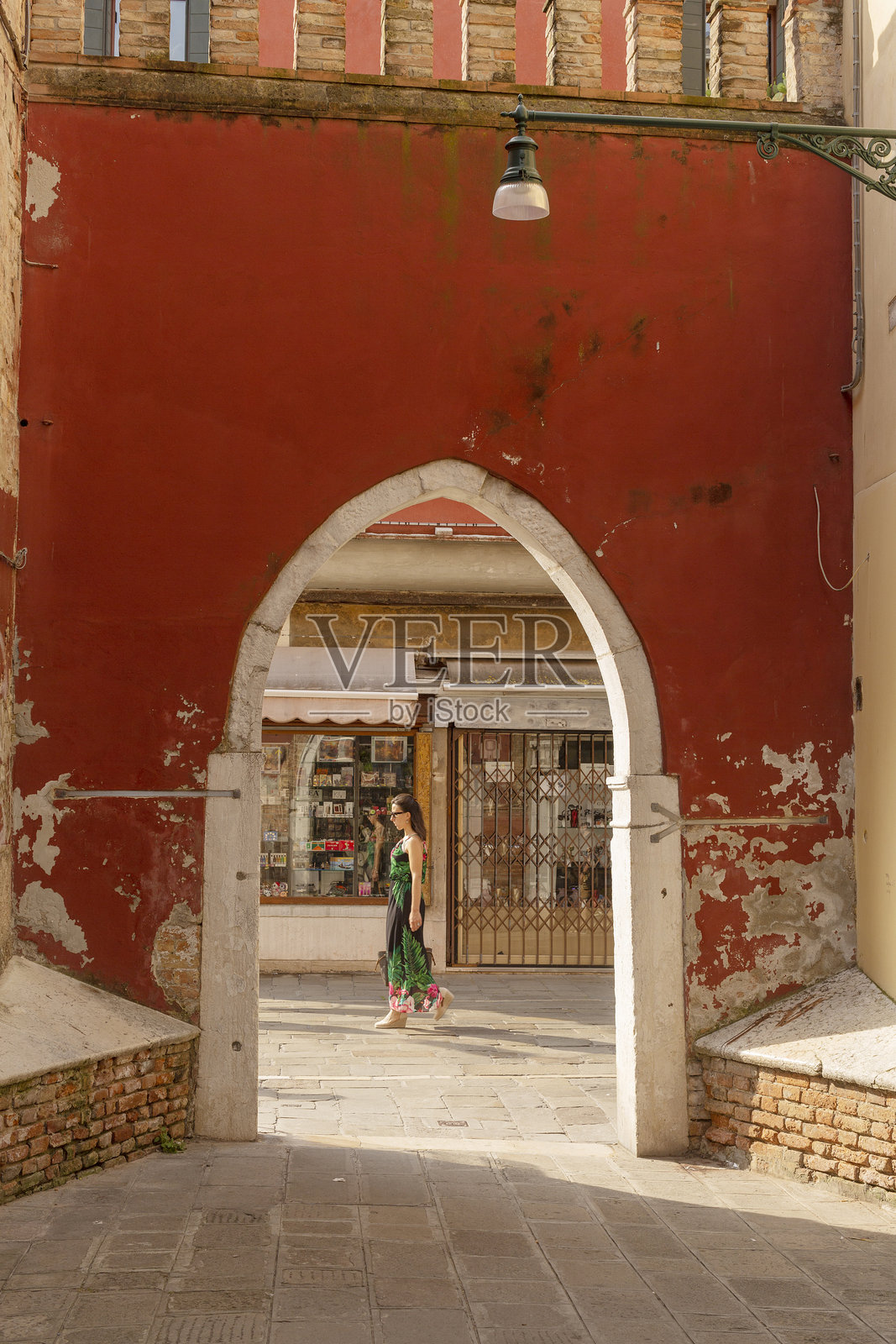 透过红色涂漆墙上的拱门，欣赏威尼斯的风景照片摄影图片