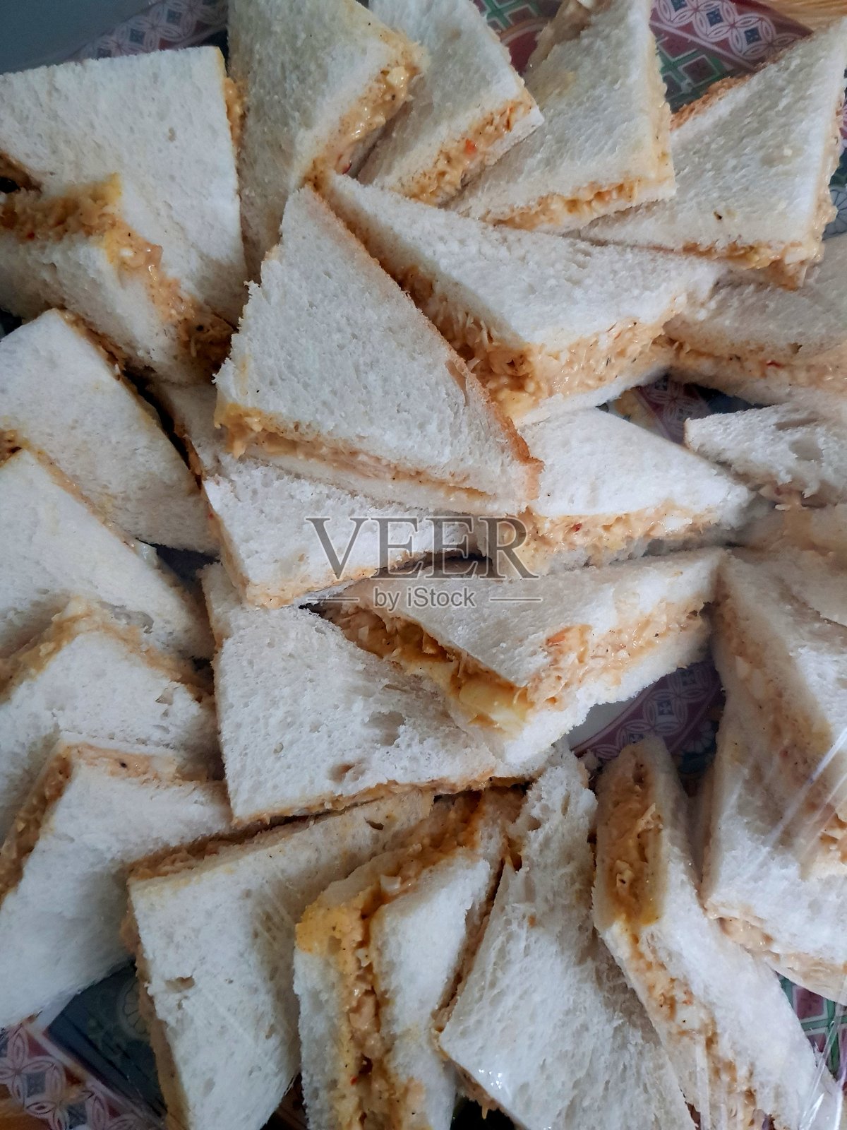 一盘用塑料袋包裹的大量鸡肉三明治特写。照片摄影图片