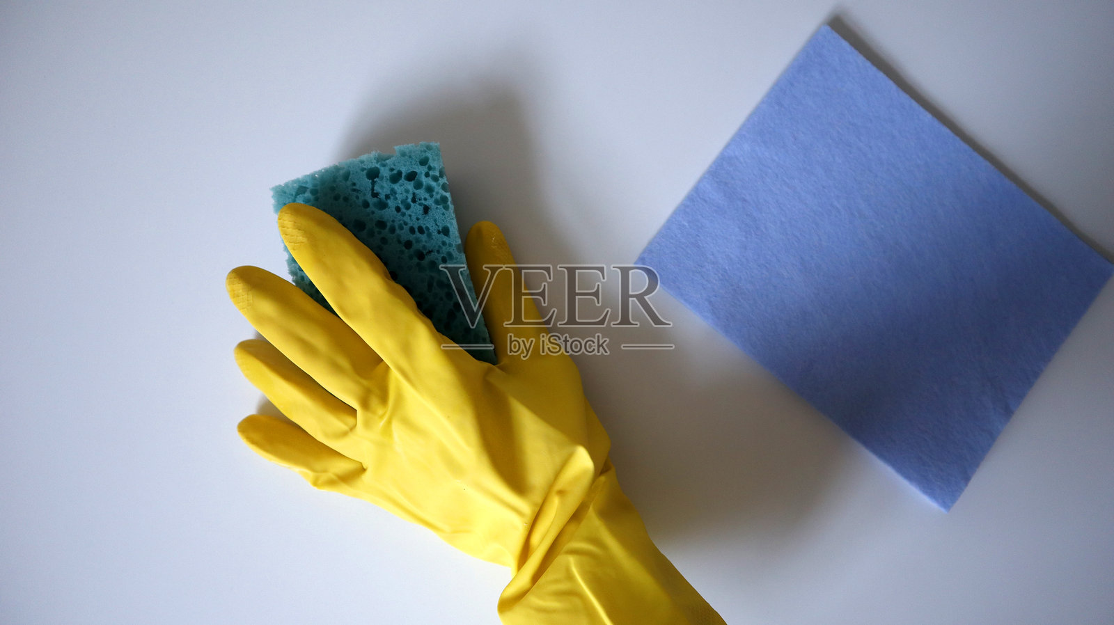 清洁过程的照片，洗涤表面。一只戴着橡胶手套的手用海绵擦拭桌子。照片摄影图片