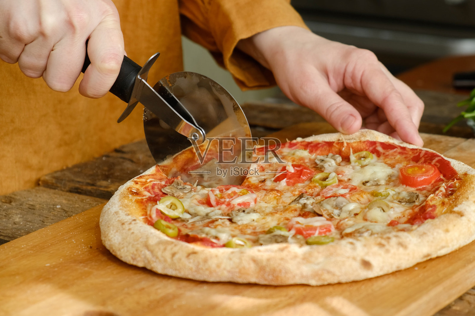 披萨刀切割着配有蘑菇和橄榄的烤披萨照片摄影图片