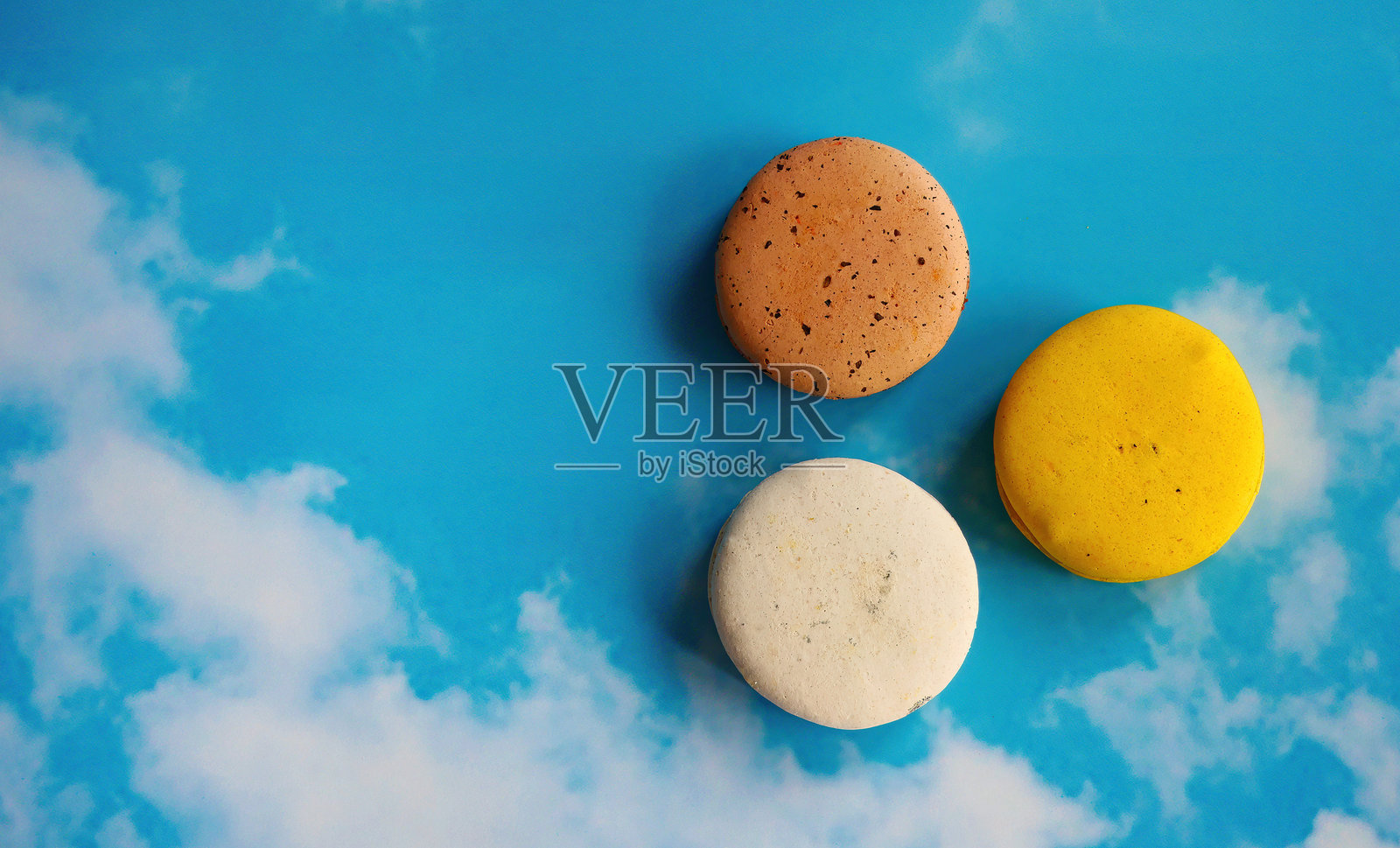 五彩缤纷的马卡龙在蓝天背景下，法式小吃，糕点食谱，杏仁粉，马卡龙饼干甜点，留白空间照片摄影图片