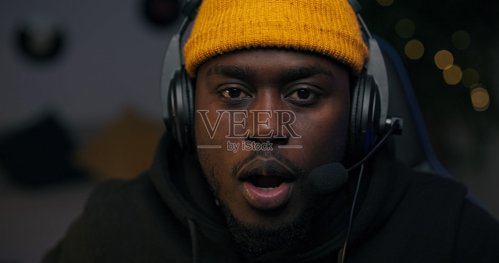 一位职业玩家被显示器上的画面震惊了。他专注地通过耳机与队友交流，制定新的策略，房间里被紫色LED灯照亮。照片摄影图片