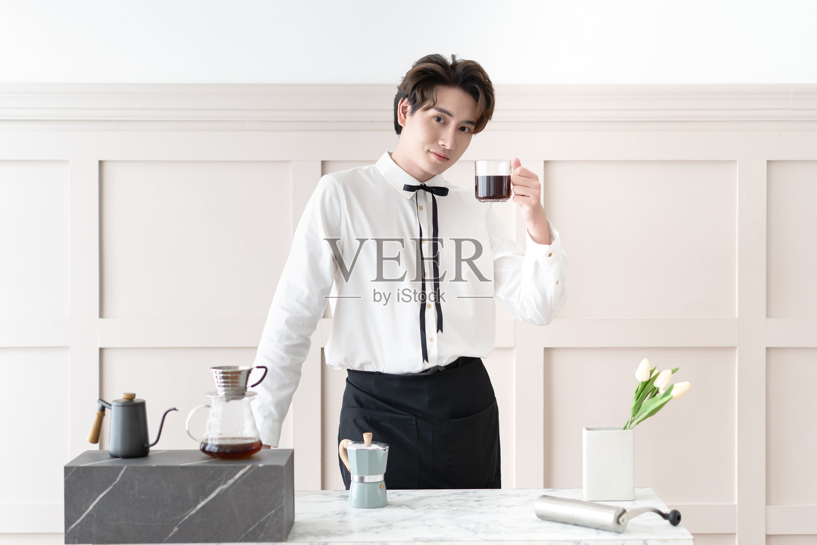 亚洲男咖啡师或微笑的年轻韩国男咖啡师在咖啡店里将热饮咖啡递给顾客。创业的小企业主。照片摄影图片