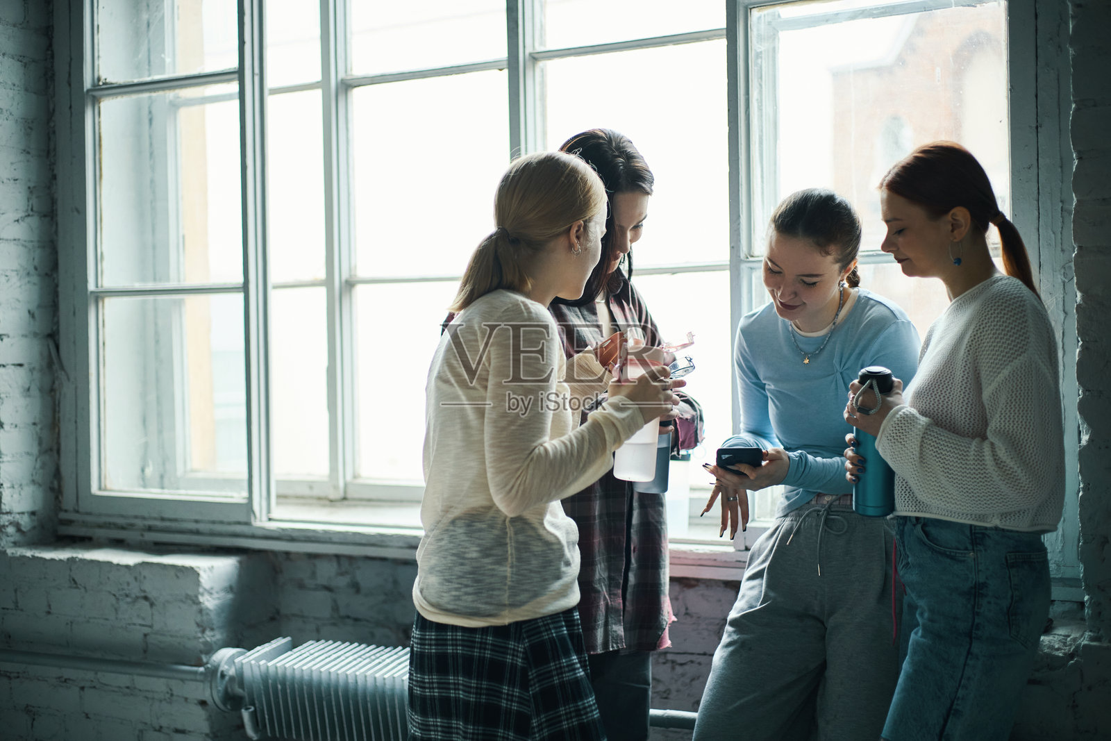 一群女学生在窗边社交照片摄影图片