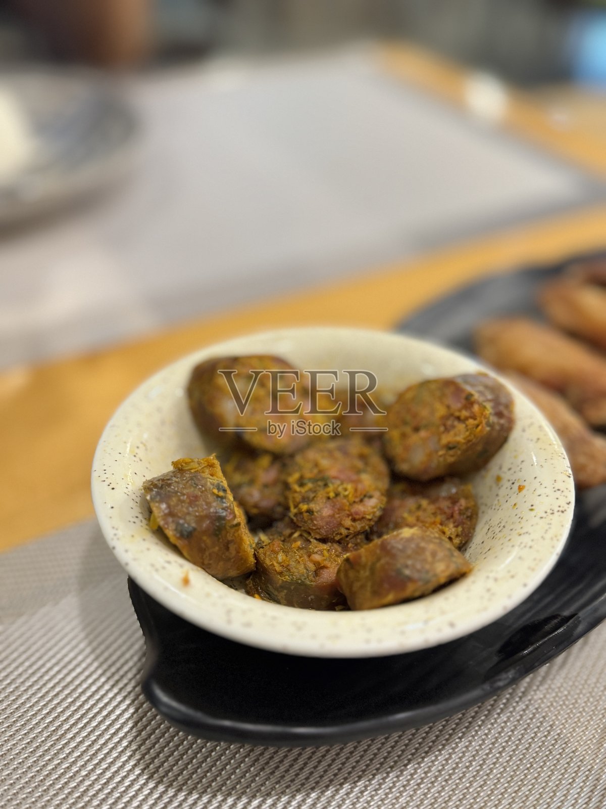 北泰香肠（Sai Oua）或伊桑香肠，切片后放在小碗中，作为一种美味芳香的传统小吃或开胃菜，充满了香草和香料。照片摄影图片