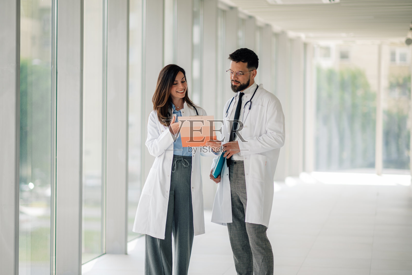 两位医生在医院走廊讨论病历照片摄影图片