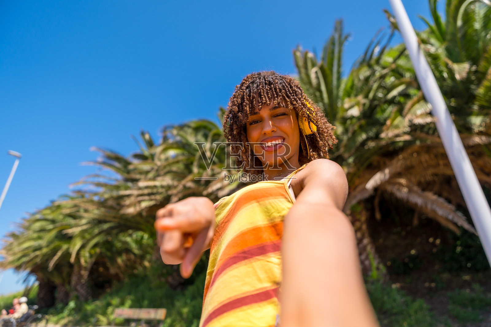 年轻女性在户外听音乐时指着镜头照片摄影图片