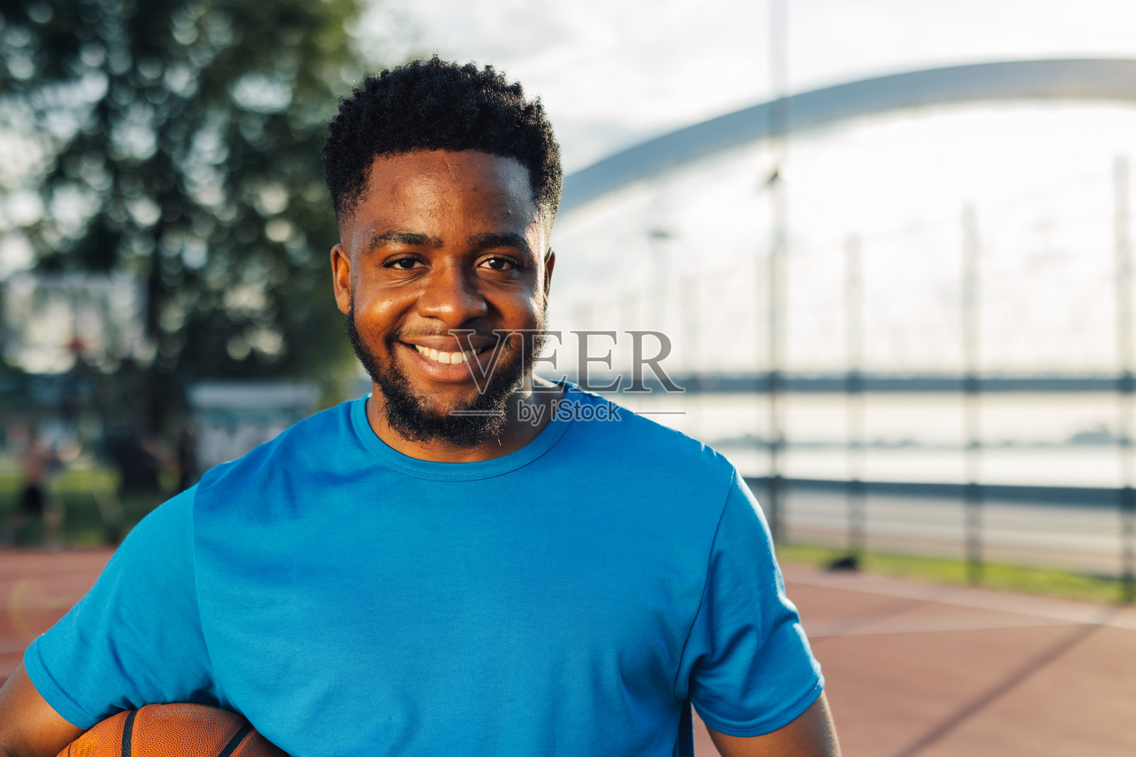 微笑的篮球运动员在户外球场上手持篮球的肖像照片摄影图片
