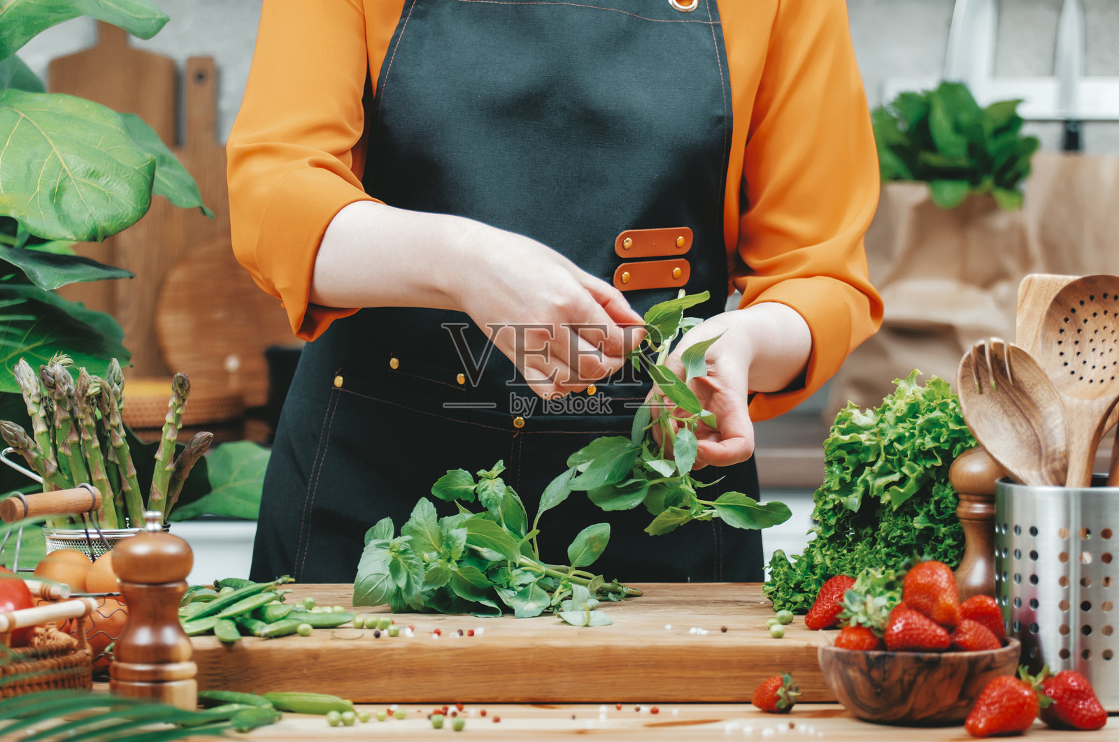 在阳光明媚的下午，一位烹饪爱好者在充满活力的厨房中新鲜准备有机蔬菜和香草。照片摄影图片