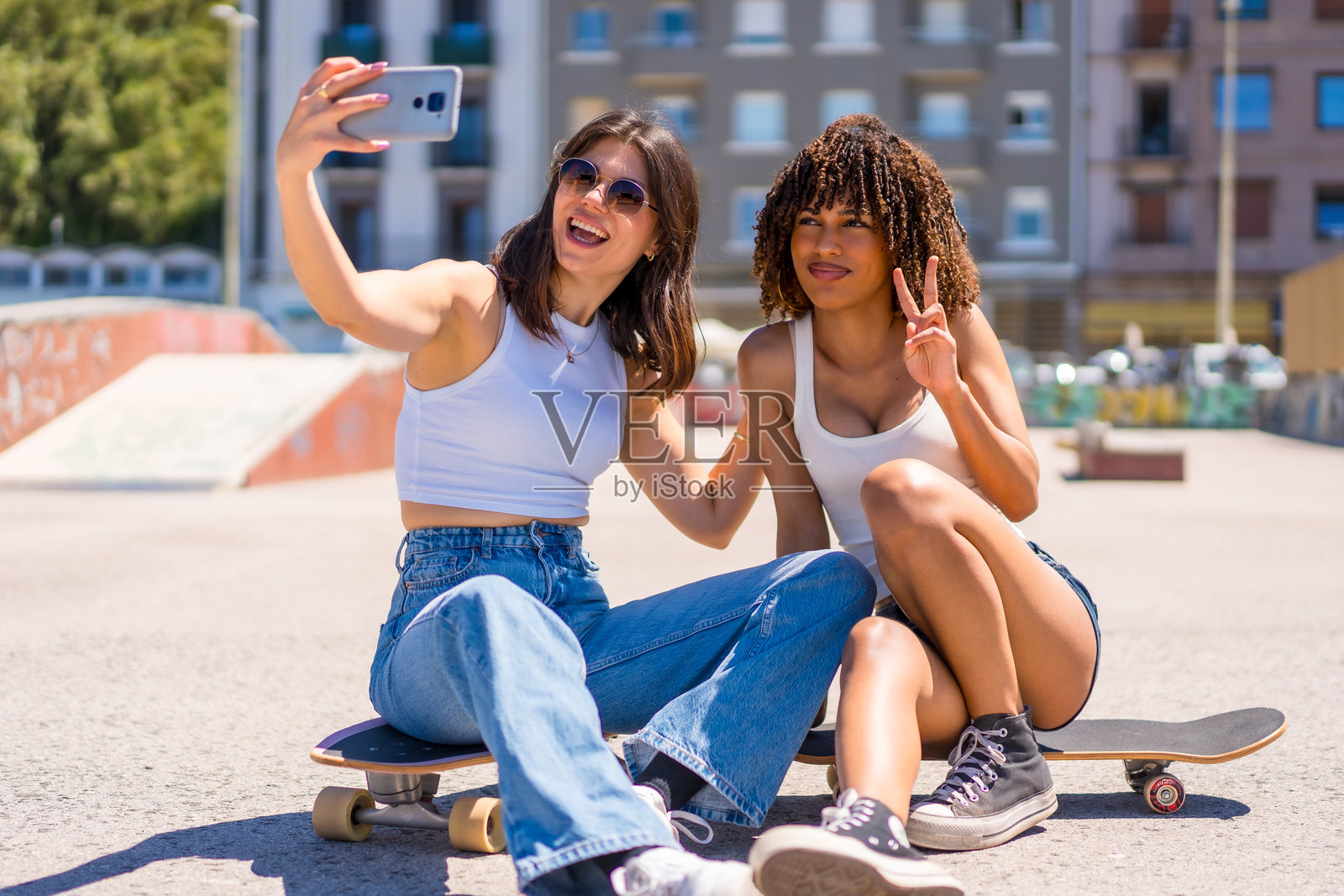 两个年轻女性坐在滑板上自拍照片摄影图片