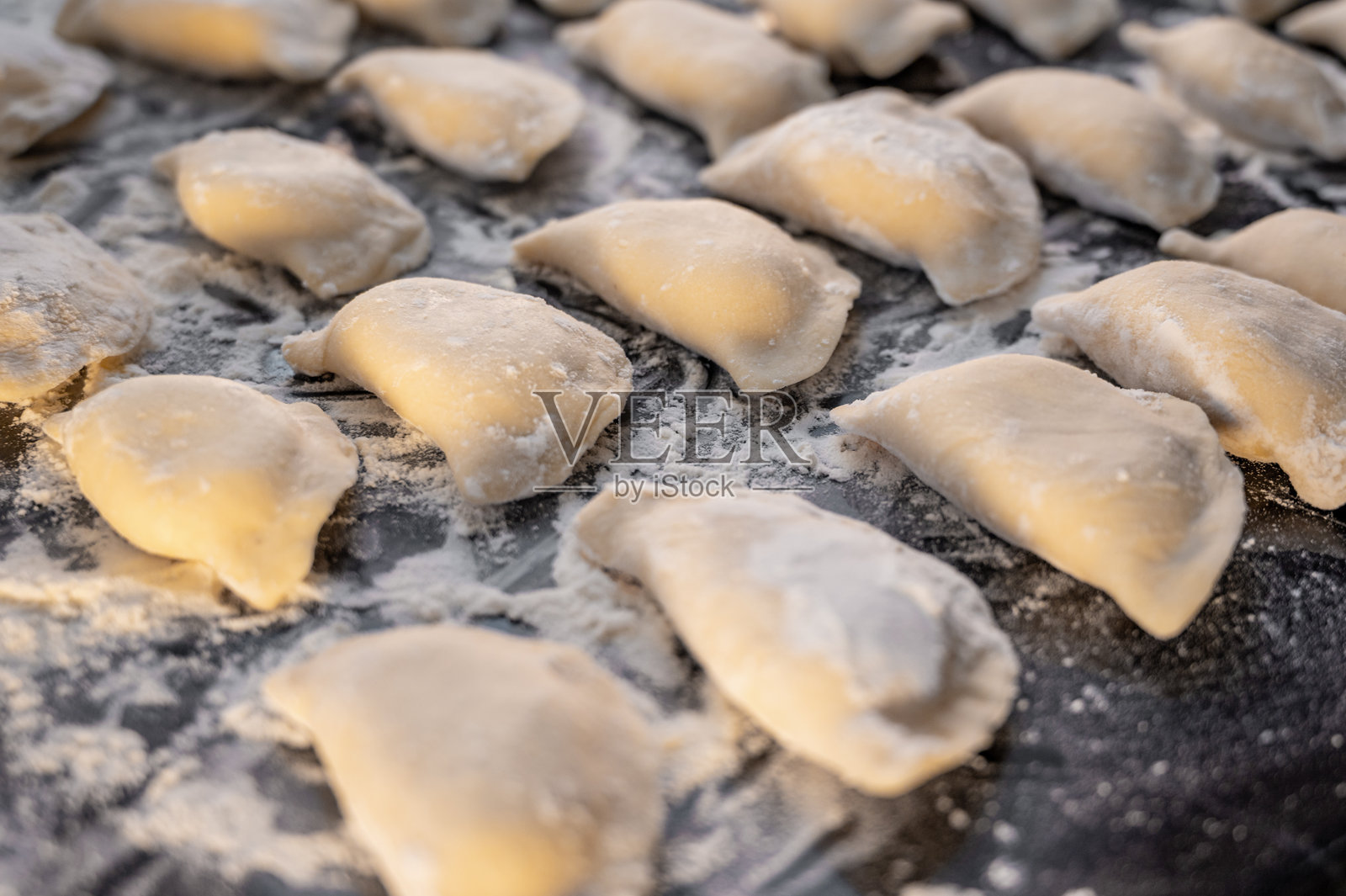 黑色台面上的生饺子，俯视图。照片摄影图片