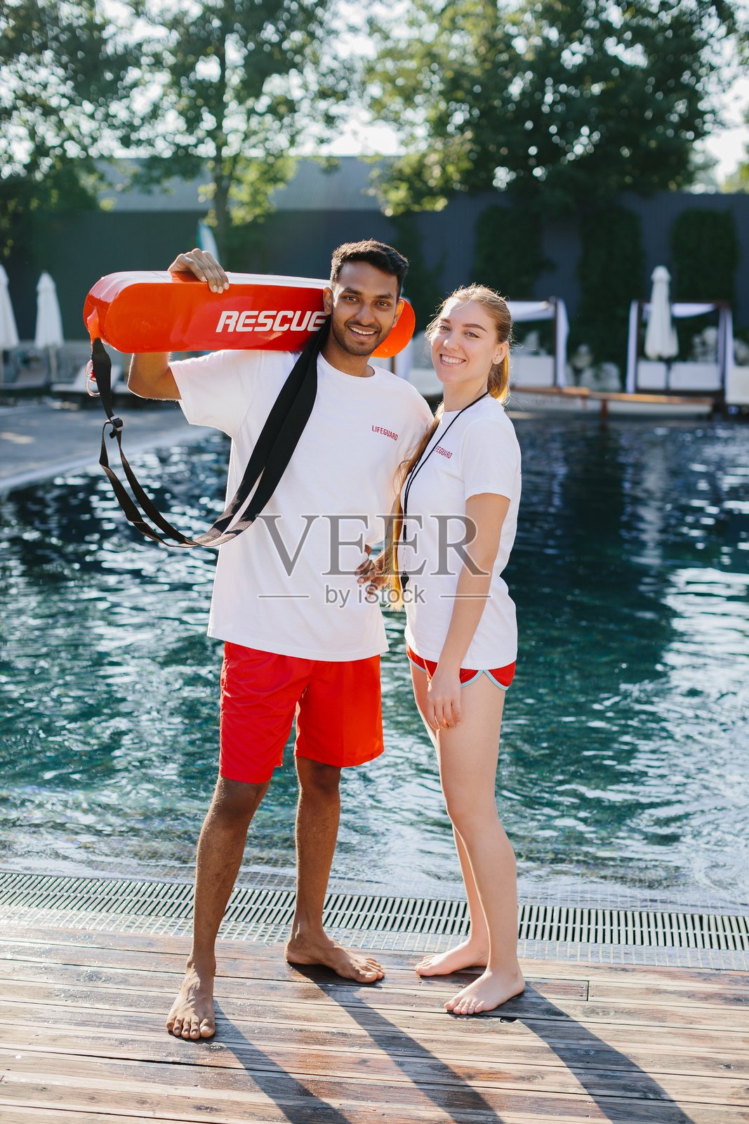 救生员在泳池边微笑，手持救生设备照片摄影图片