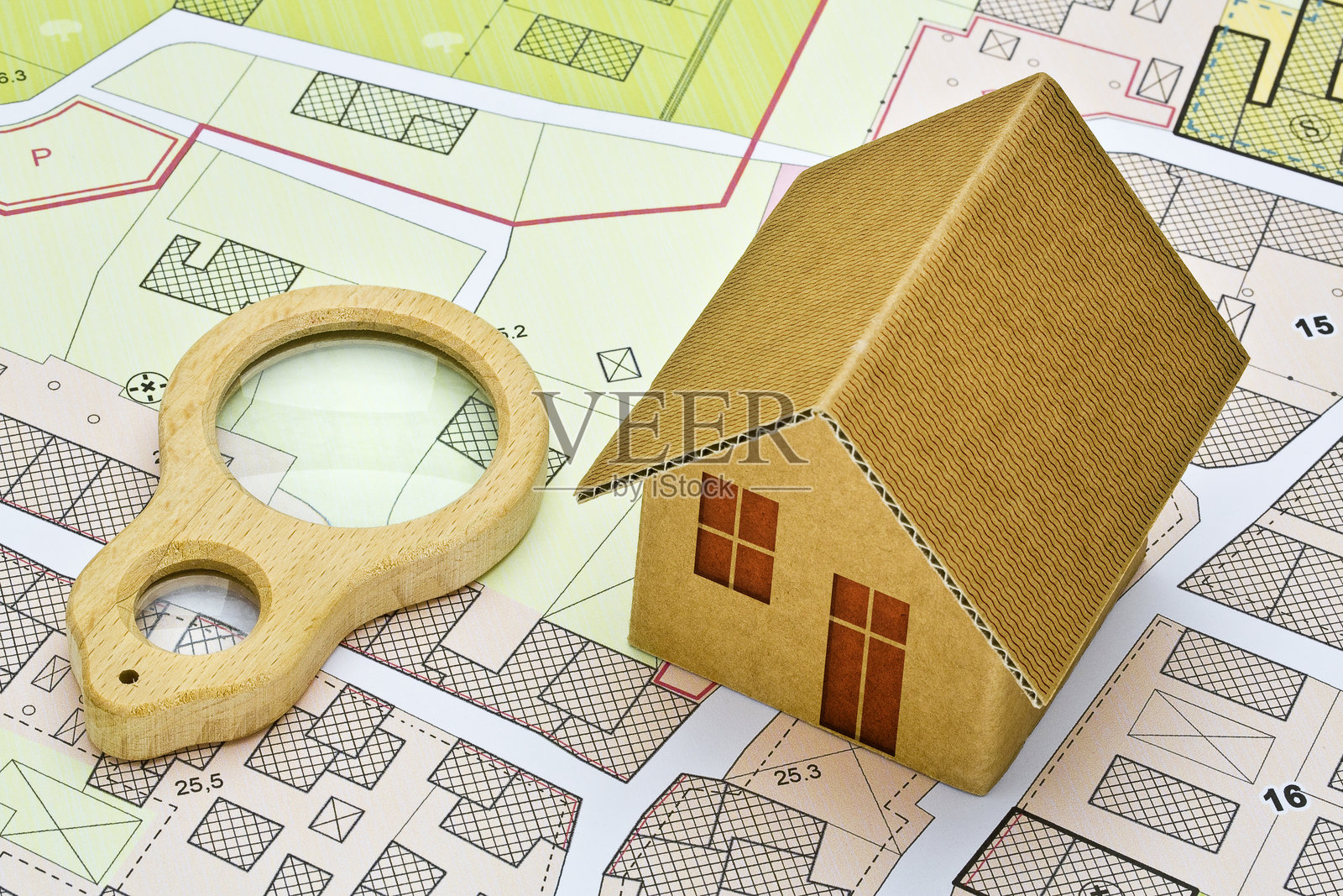 虚构的地籍图，包含建筑物、土地分 parcel 和空地 - 物业登记和房地产概念，配有木制放大镜 - 注意：地图背景完全是虚构的，不代表任何真实地点。照片摄影图片