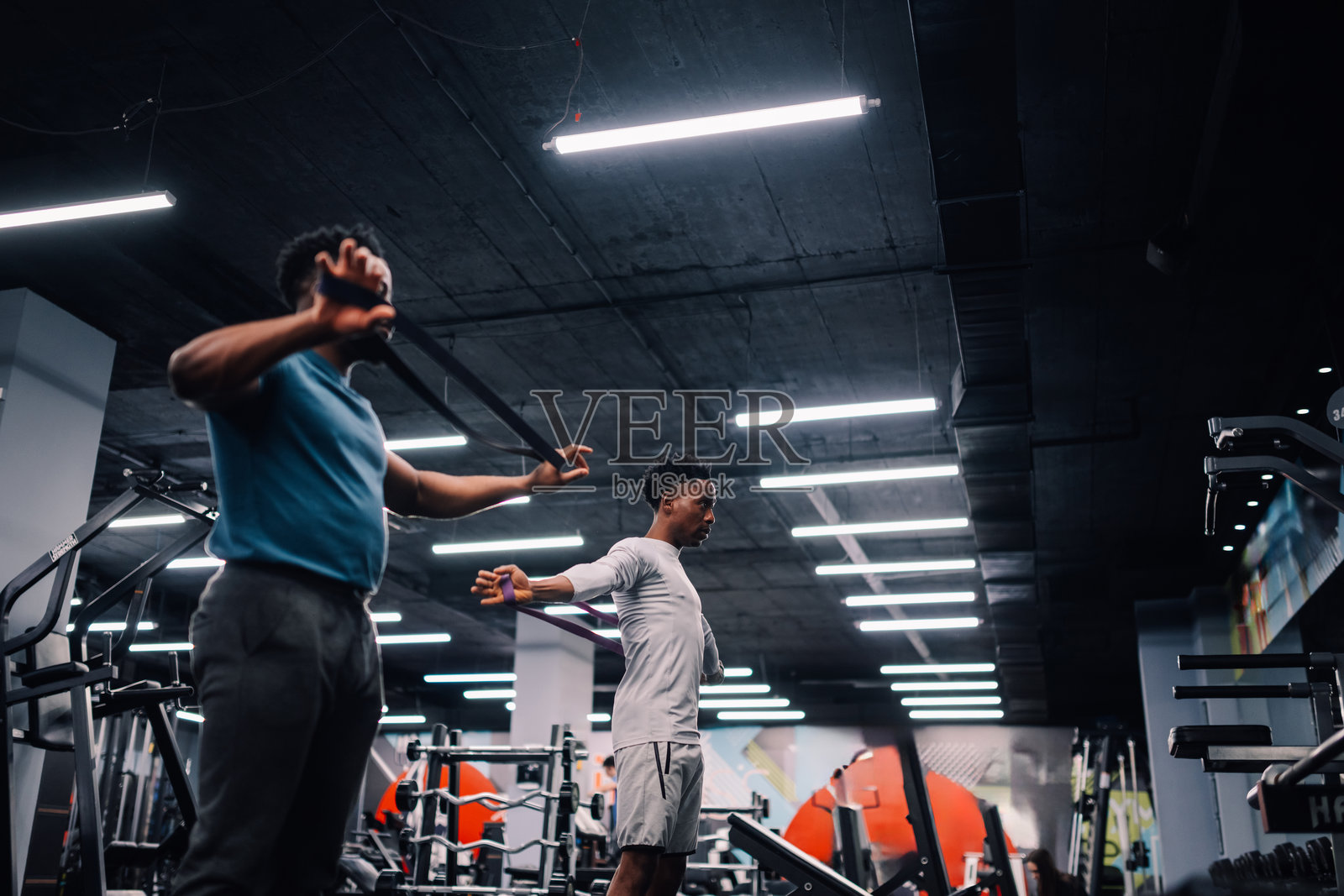 两名年轻男子在健身房使用阻力带训练照片摄影图片