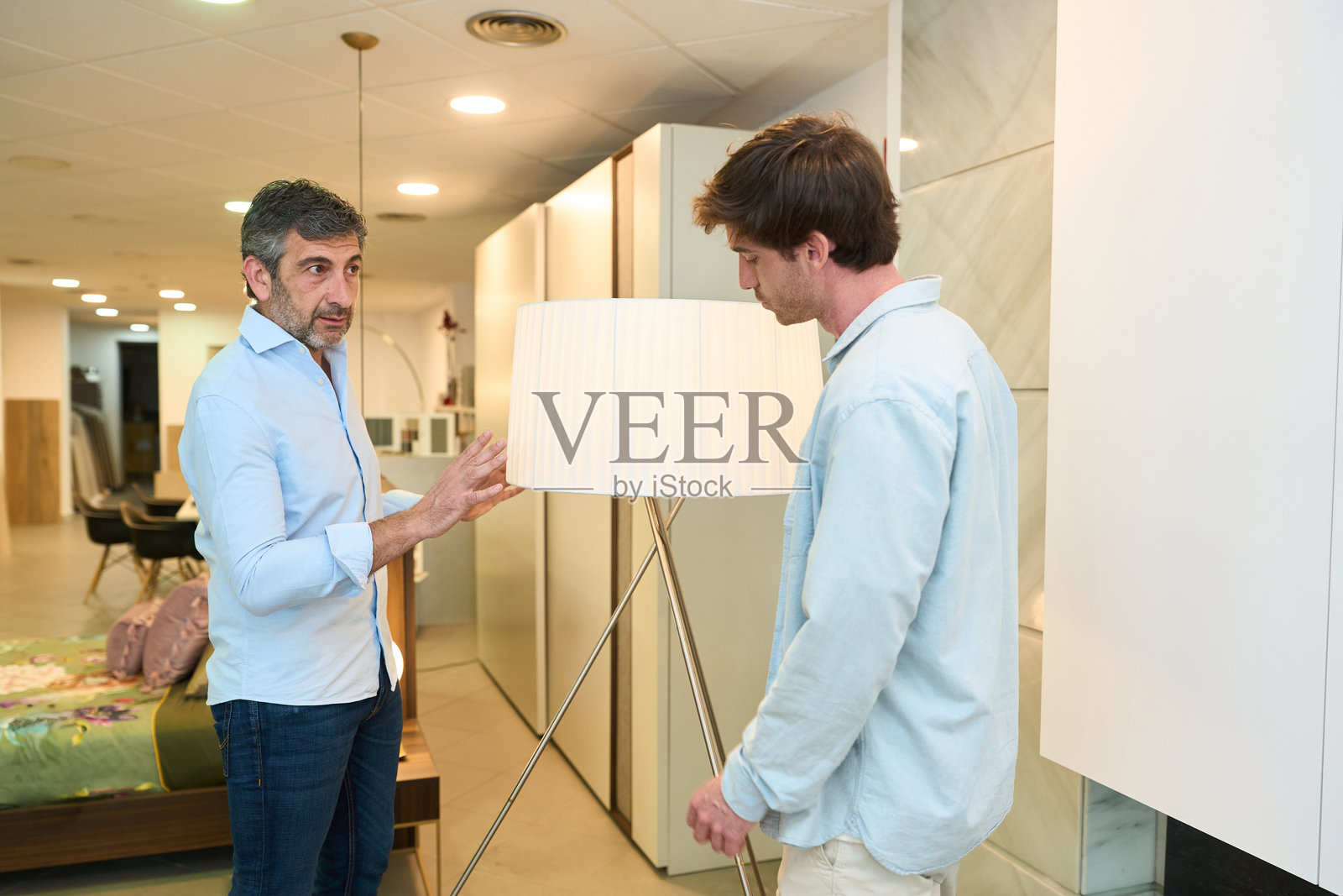 室内设计师在家具店向一对夫妇展示落地灯照片摄影图片