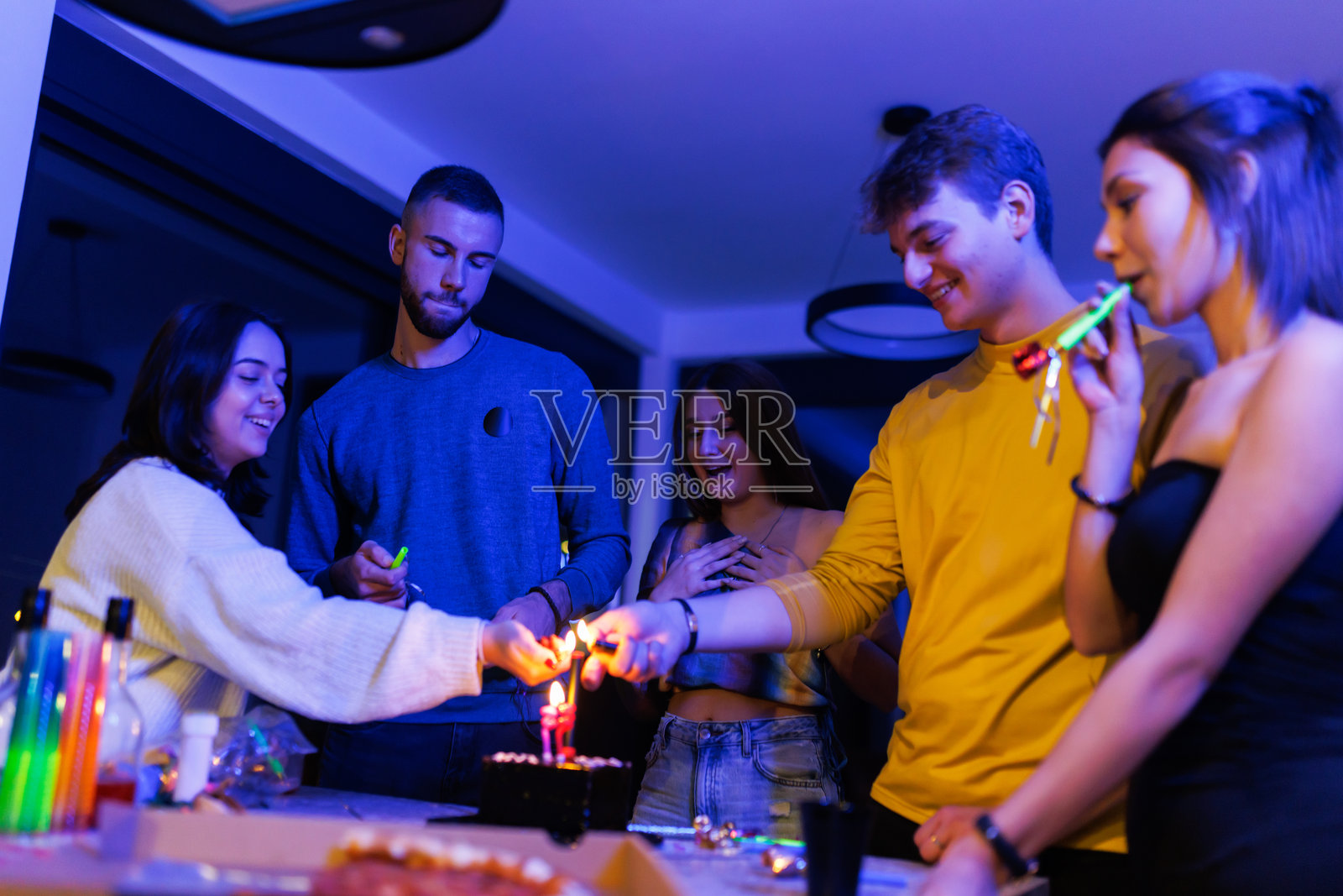 年轻朋友们在现代室内聚会庆祝，享受蛋糕和欢笑照片摄影图片