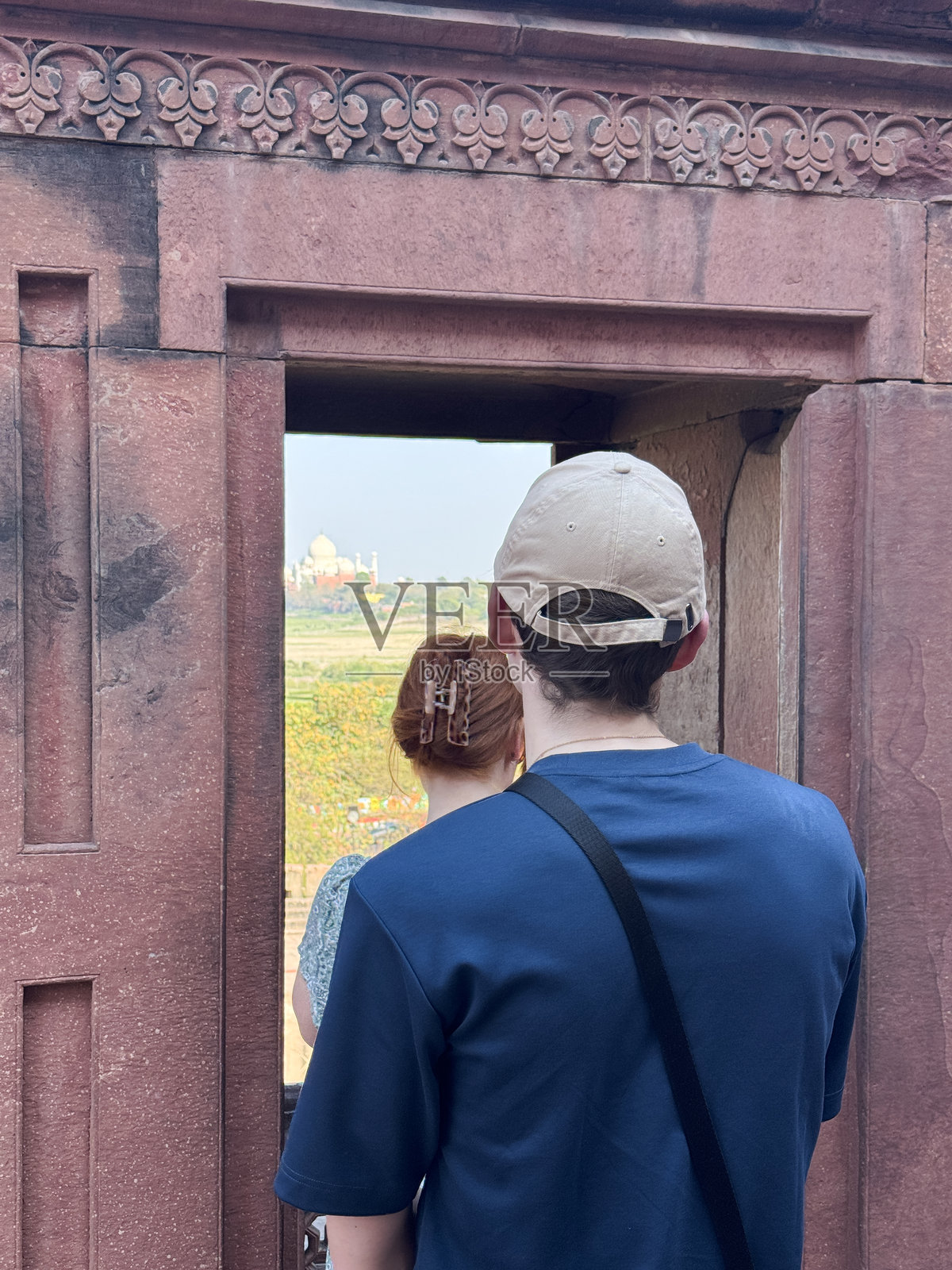 游客从拉尔基拉红堡的窗户拍摄白色大理石泰姬陵宫殿、乡村和天际线的照片，背景是有雾霾的天空，视角来自于阿格拉堡，北方邦，印度。照片摄影图片