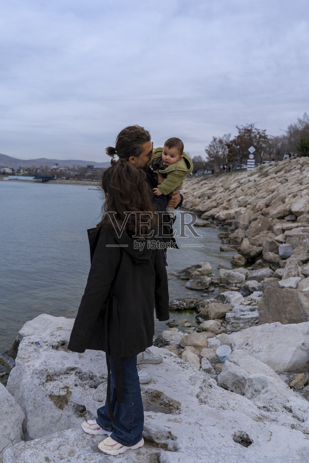 小女孩和小男孩在海滩路上与父亲一起玩耍。父亲和他的两个孩子一起享受快乐时光。照片摄影图片