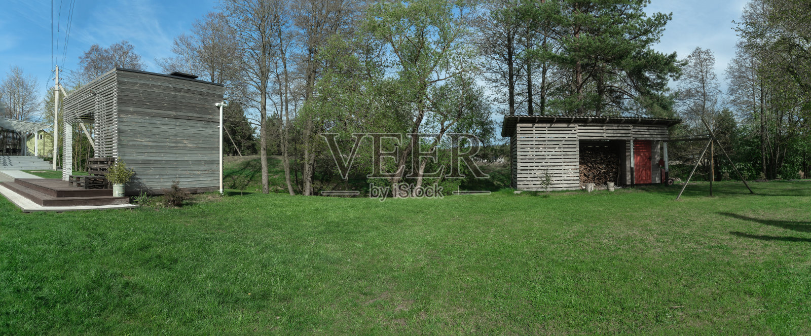 一片修剪整齐的草坪旁边是一座迷人的家。这里是完美的野餐地点，配有舒适的凉亭和小屋，四周环绕着郁郁葱葱的绿树。照片摄影图片