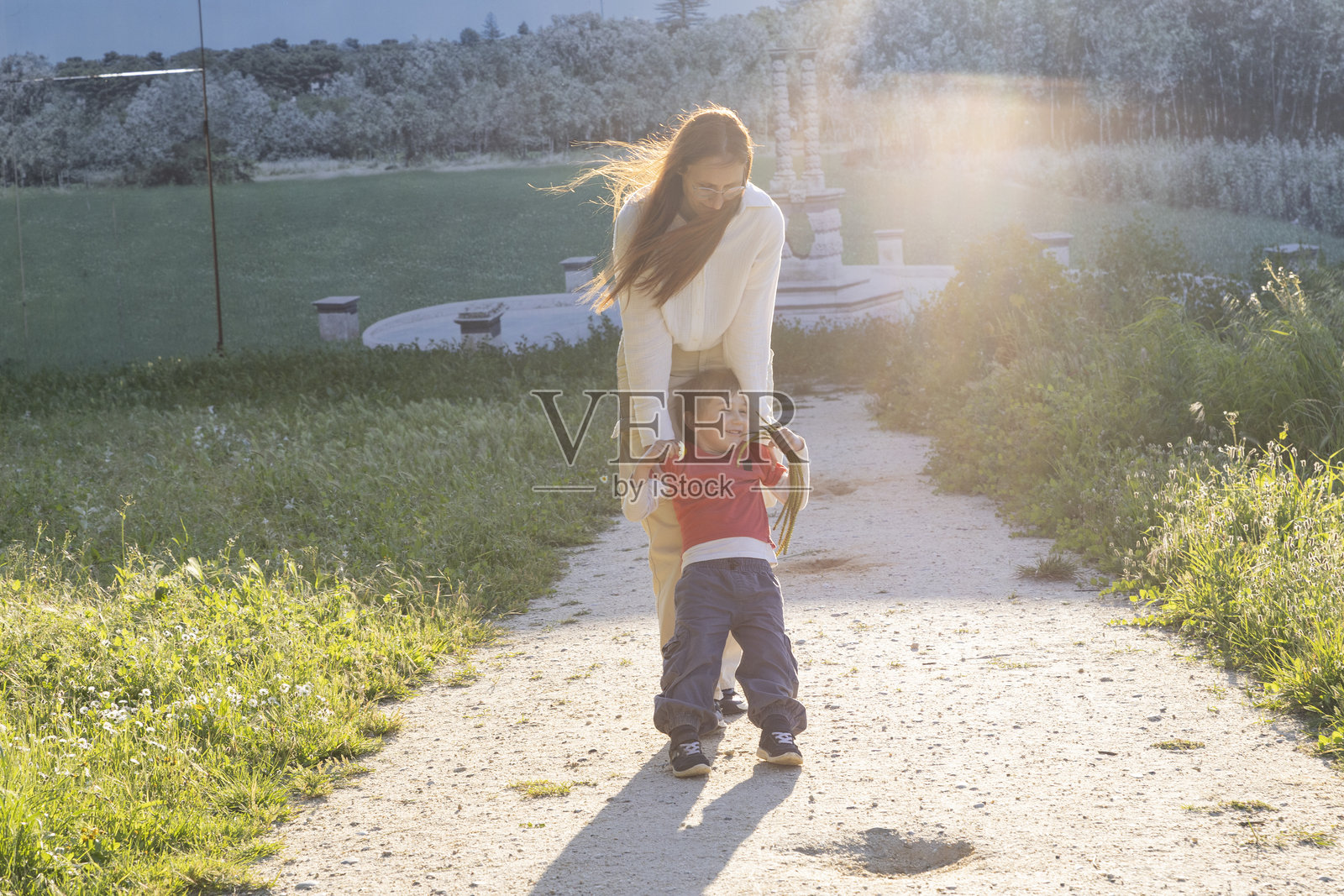 母亲在日落时分的公园里摇摆她的儿子照片摄影图片