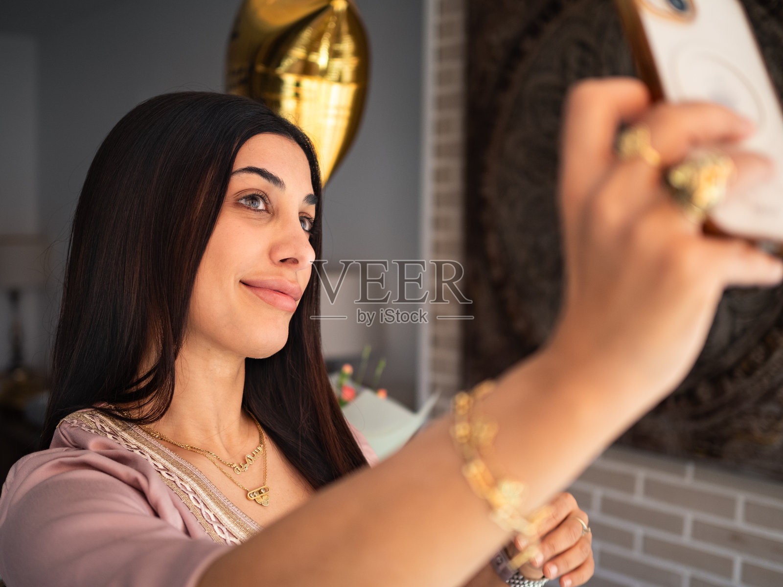 阿拉伯女性在温馨的室内环境中微笑着自拍，周围装饰着庆祝的元素。照片摄影图片