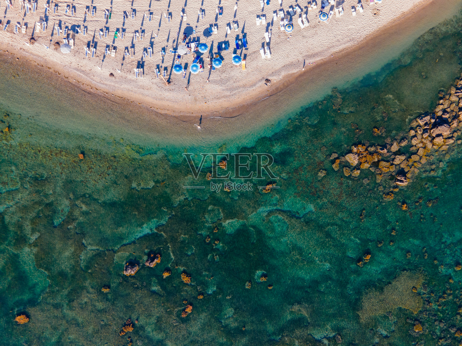 沙滩的鸟瞰图，阳光下的沙滩上有躺椅和伞，旁边是清澈的海水照片摄影图片