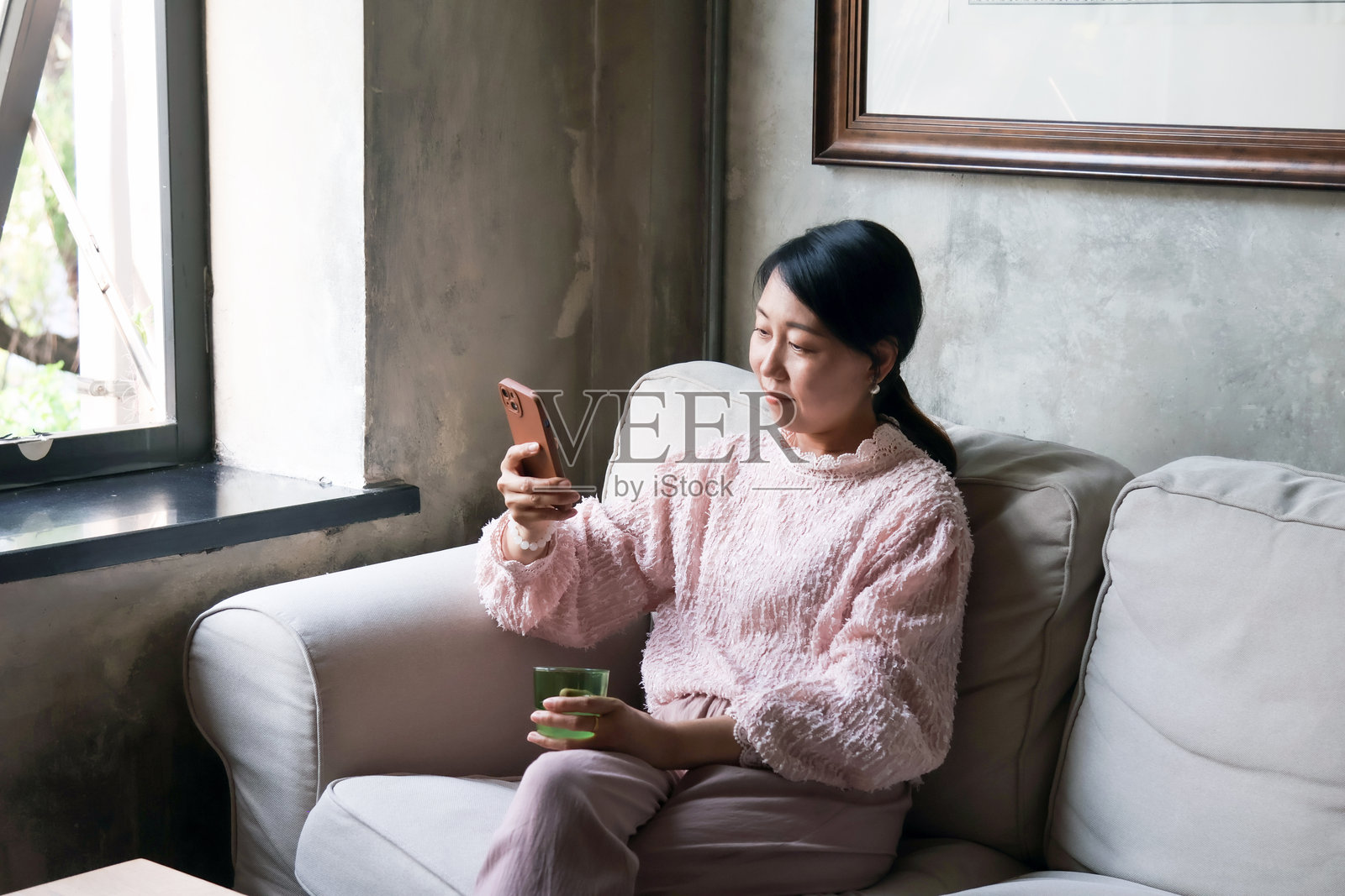 一位亚洲女性在咖啡店里用手机聊天。照片摄影图片