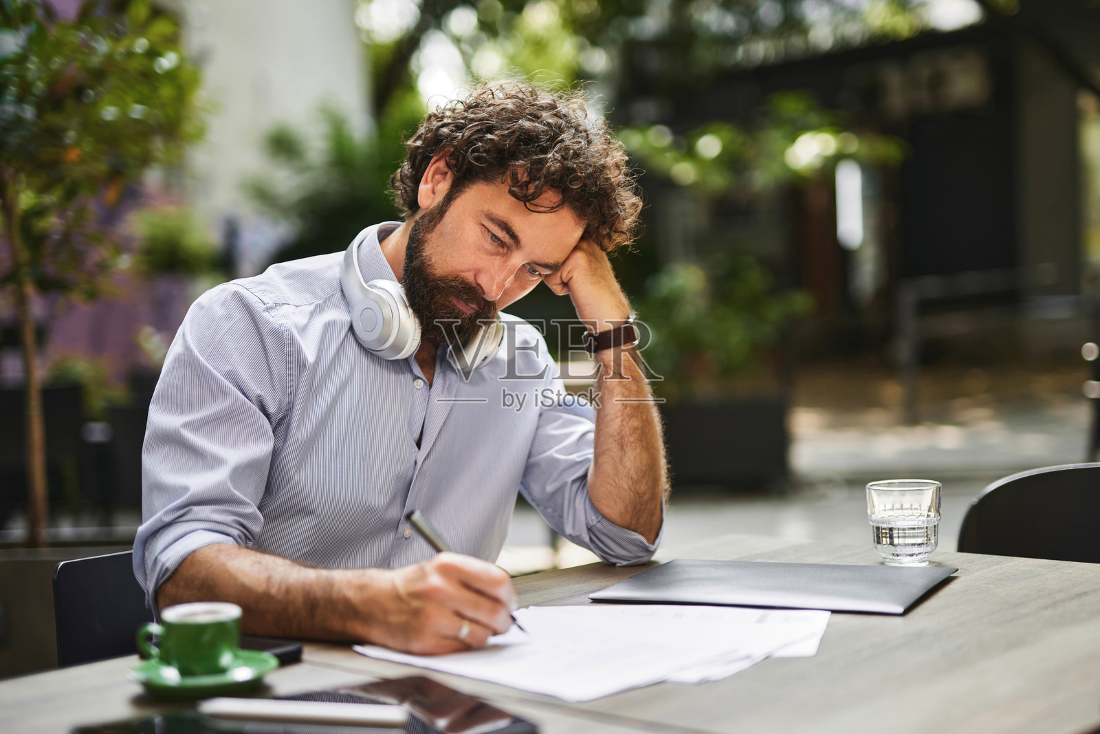 专注的企业家在户外咖啡馆远程工作，做笔记并思考商业策略照片摄影图片