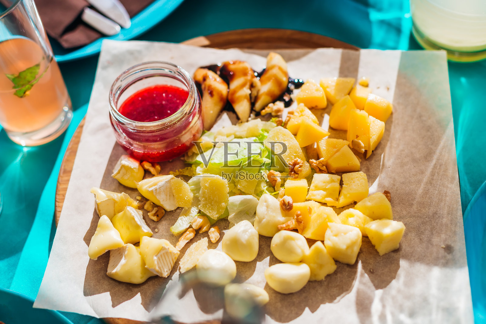 木板上摆放着美味的奶酪和一瓶酱汁。照片摄影图片