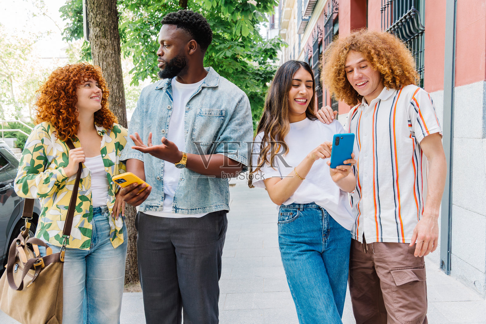 年轻旅行者在城市人行道上聚集，查看智能手机，边导航城市街道边分享兴奋的对话和旅行故事照片摄影图片