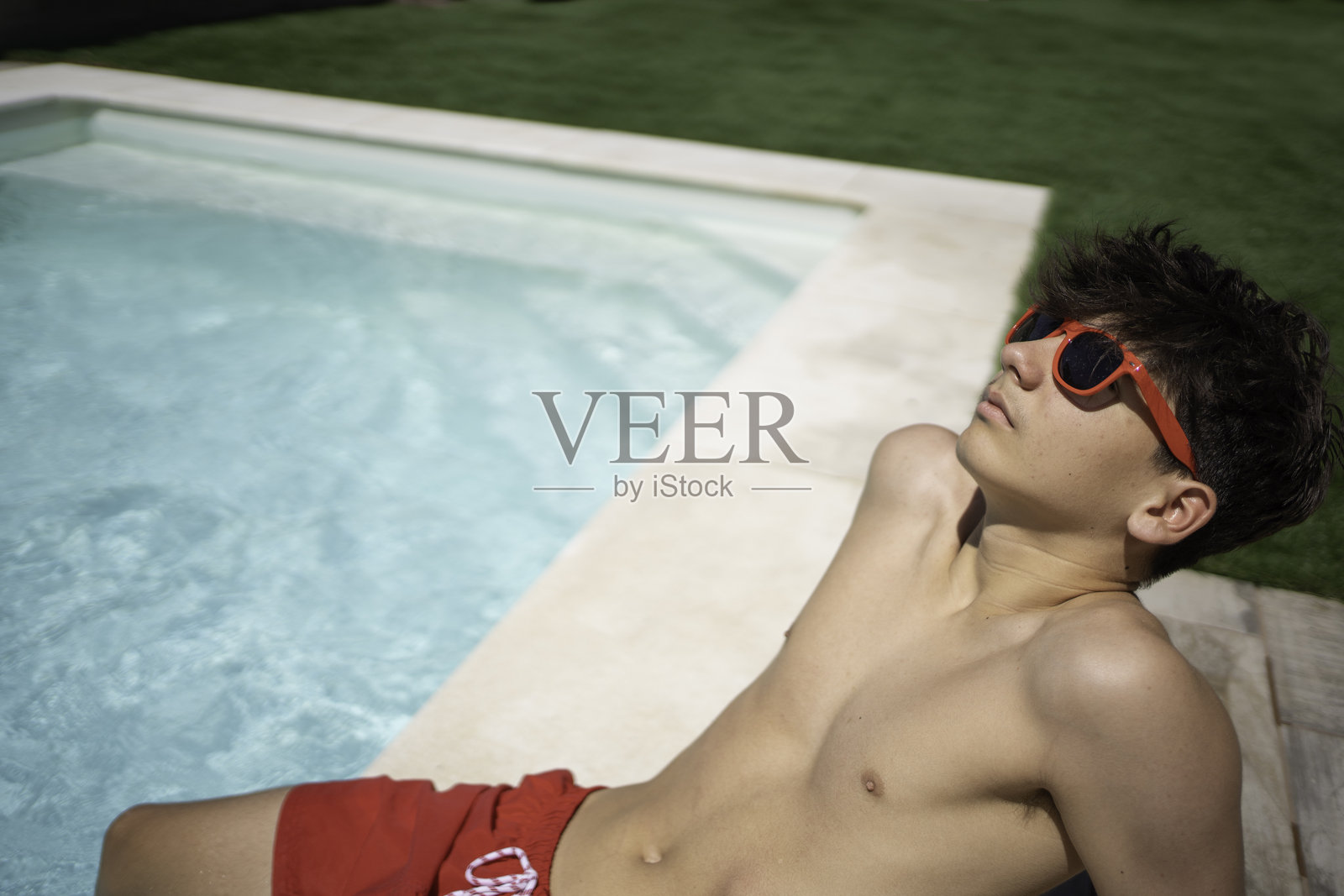 青少年在阳光明媚的日子里悠闲地待在泳池旁照片摄影图片