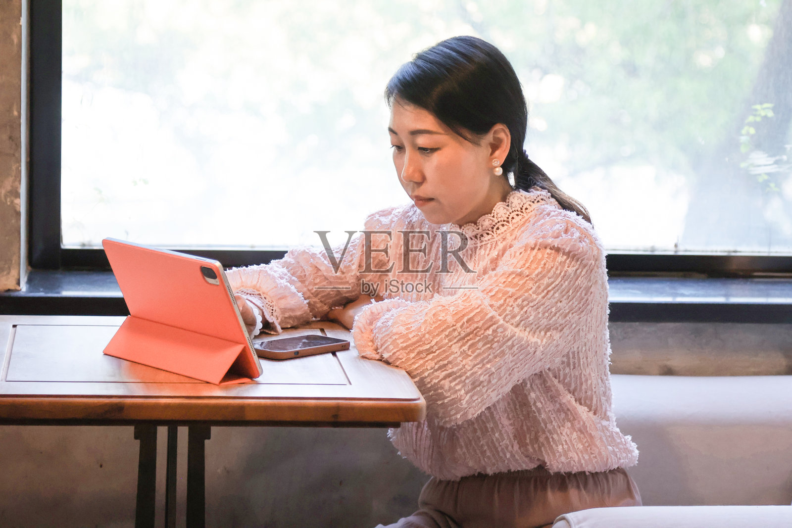 一位亚洲女性在咖啡店使用平板电脑。照片摄影图片