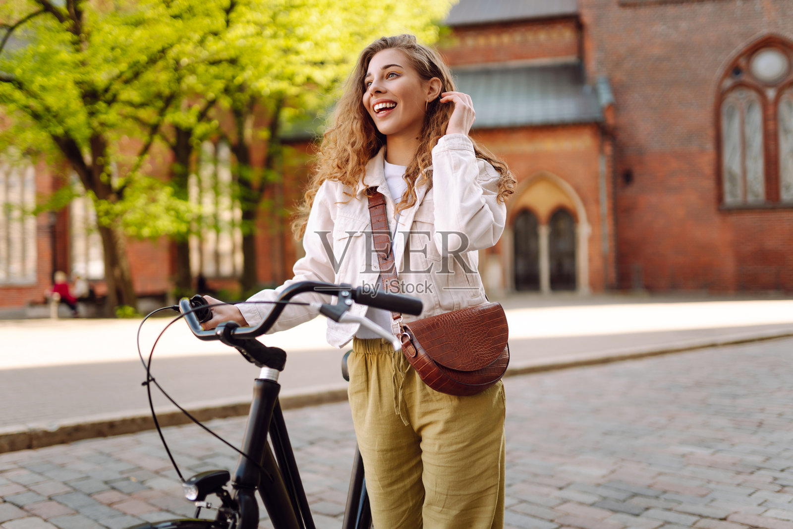 阳光明媚的城市街道上，快乐的女性骑着自行车享受散步时光。照片摄影图片