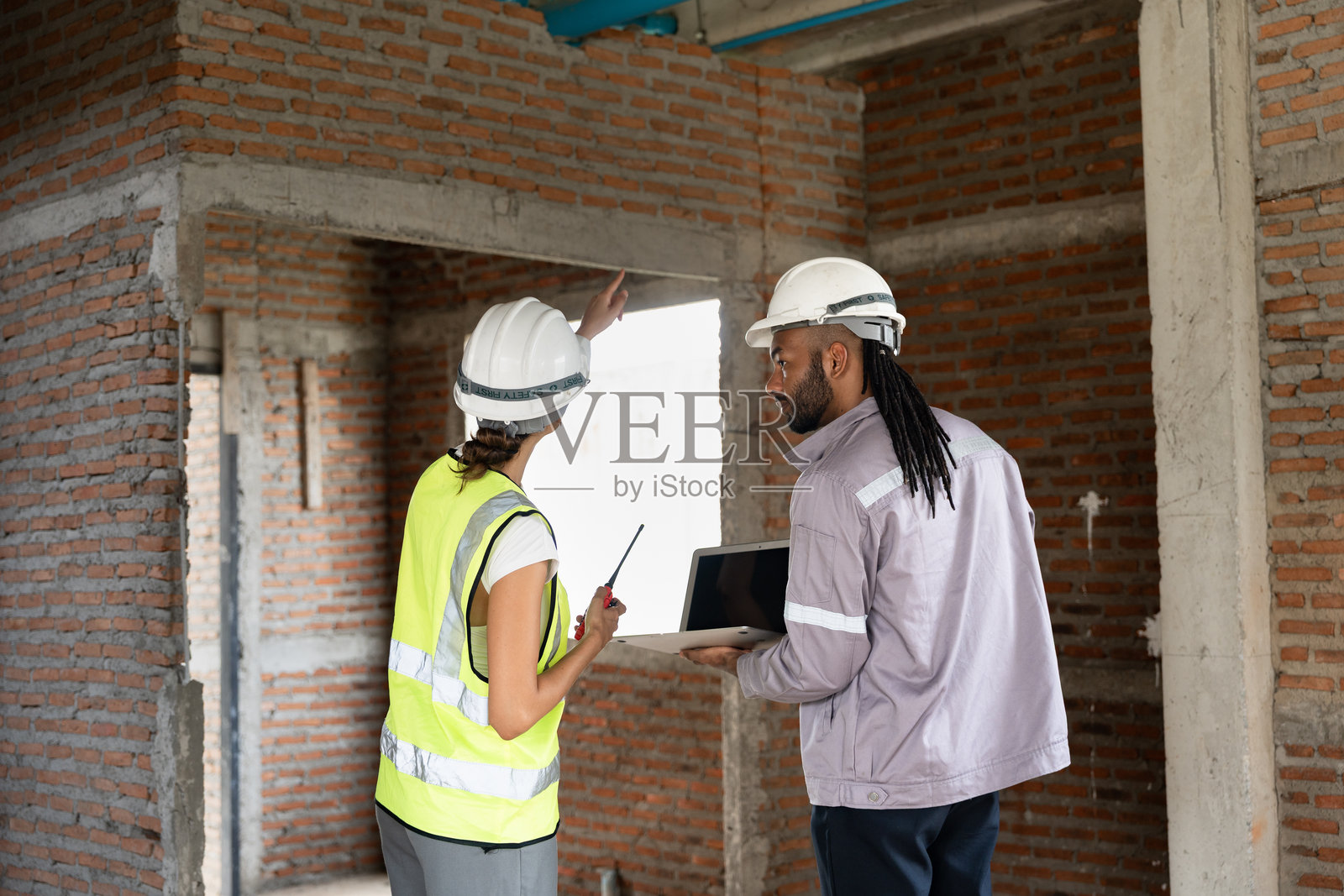 两名工程师建筑工人。工头在施工现场使用笔记本电脑工作。照片摄影图片