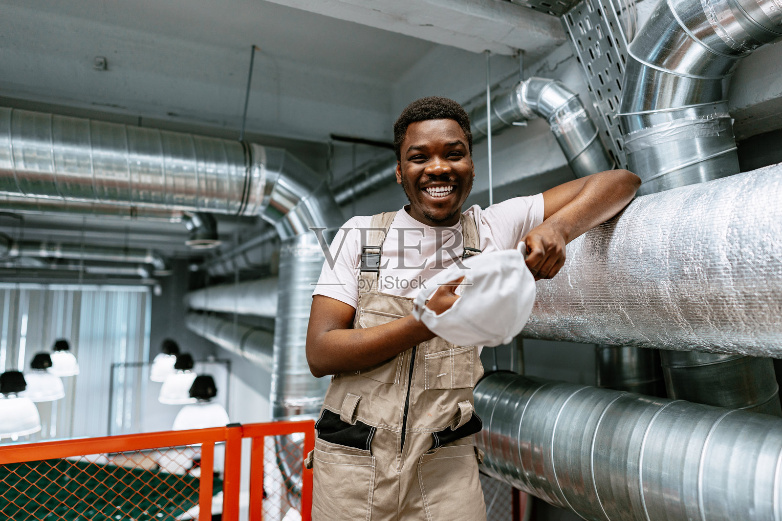 维护工人在白天的工业环境中微笑着摘下安全帽照片摄影图片