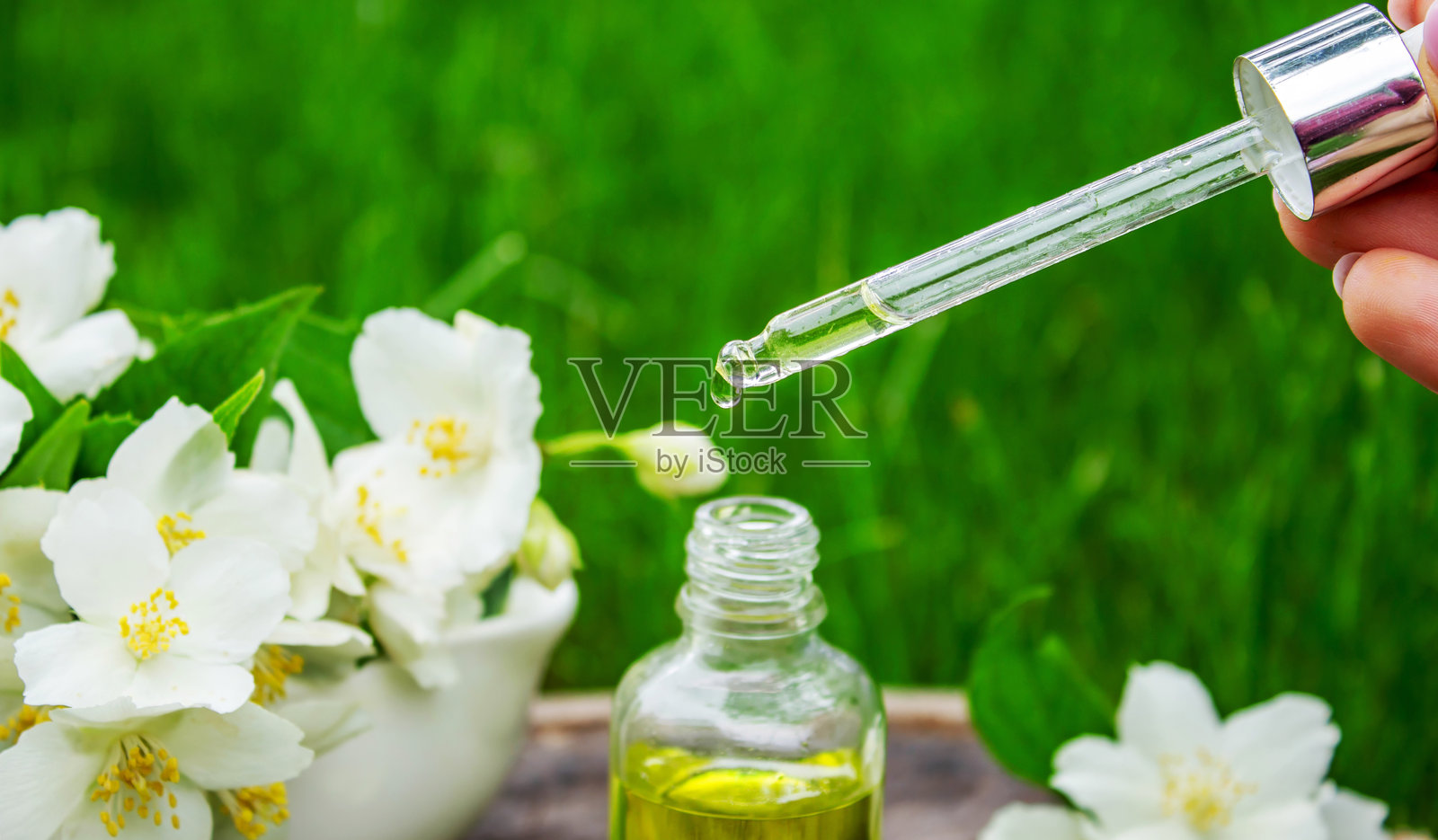 玻璃瓶中的茉莉花精油和茉莉花。油类。照片摄影图片