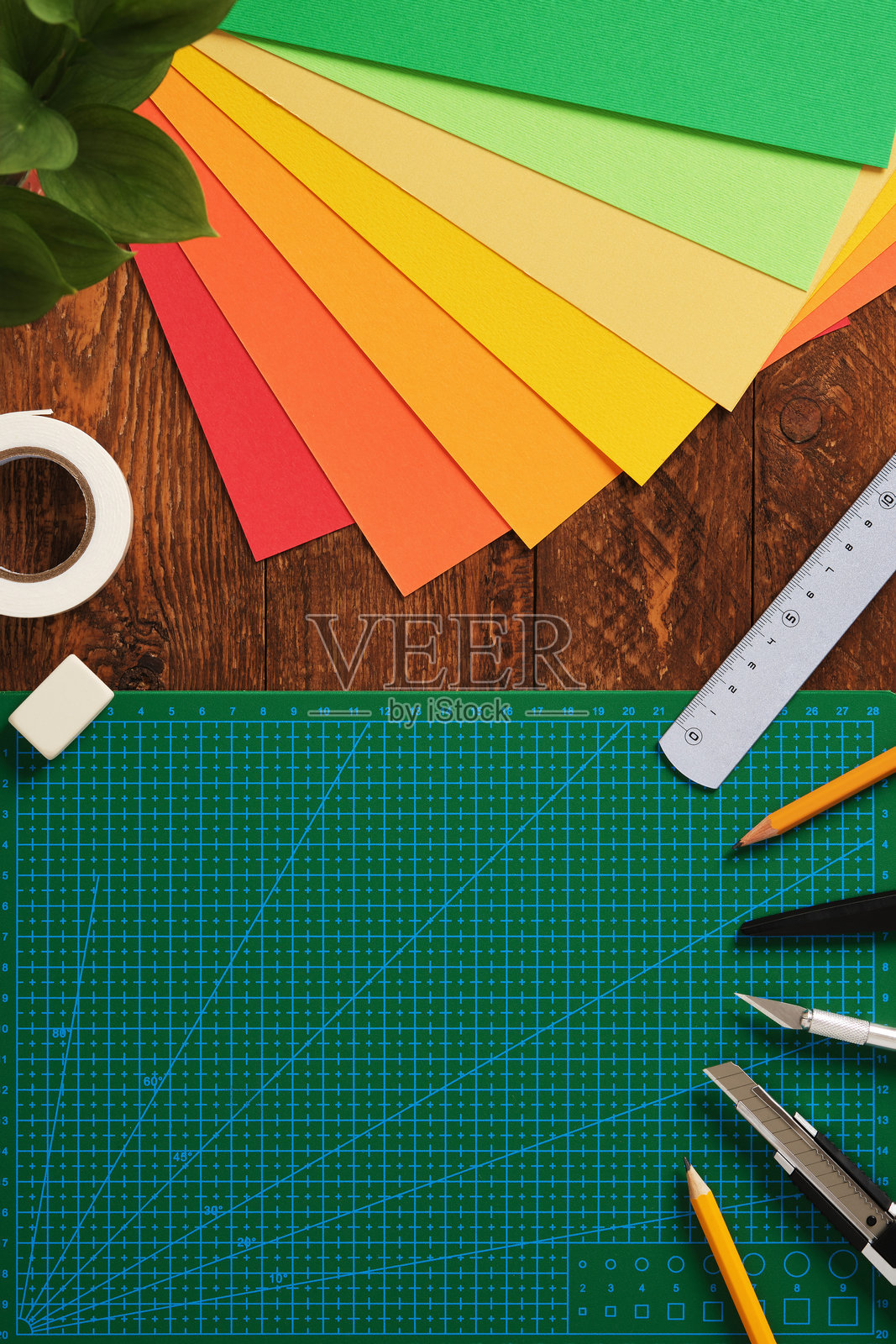 纸艺手工。整齐排列的彩色纸张、绿色切割垫、剪刀、工艺刀、铅笔、胶水和尺子。木质背景，留有文字空间。照片摄影图片