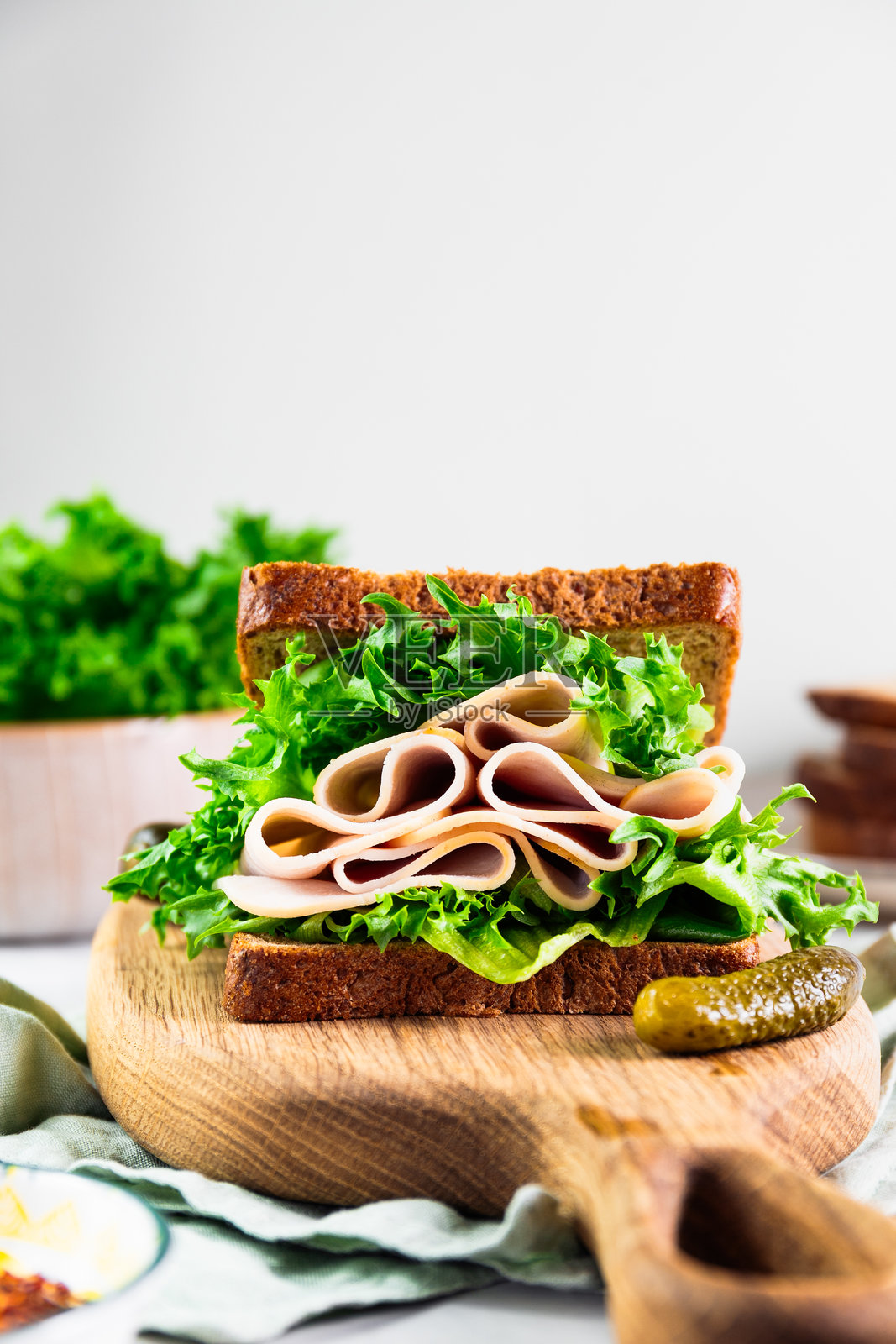美味的火鸡火腿三明治，搭配新鲜的绿色生菜，夹在全麦面包中，放在木板上。照片摄影图片