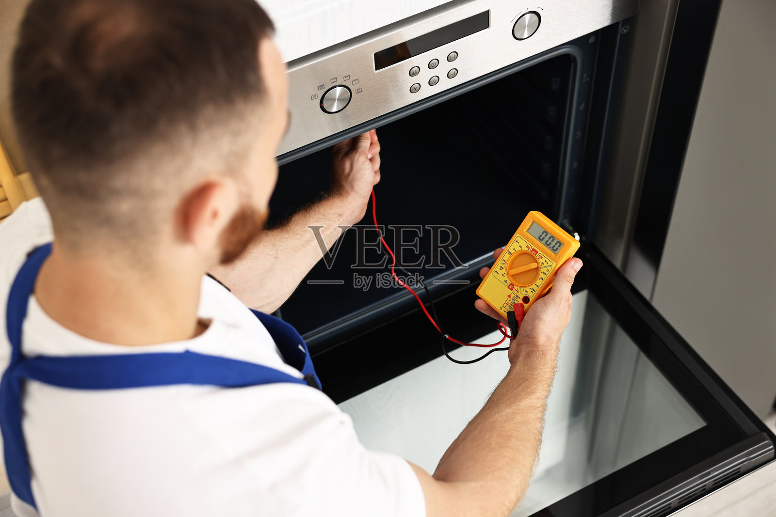 维修工正在用万用表测试烤箱加热元件，俯视图照片摄影图片