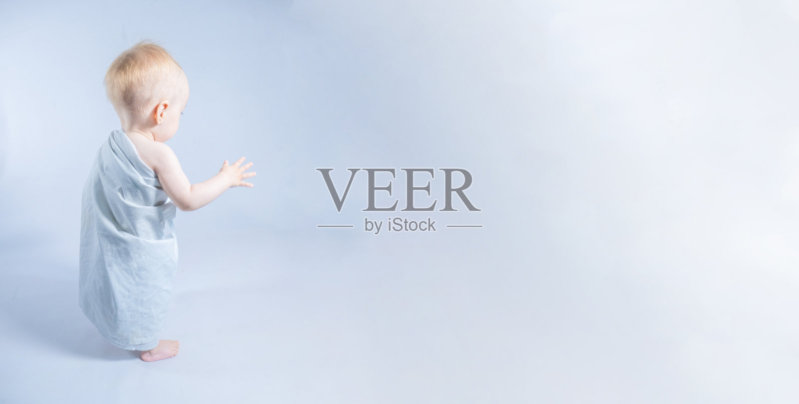 穿着托加的幼年羊指向一个明亮的空间，横幅上留有文字位置。照片摄影图片