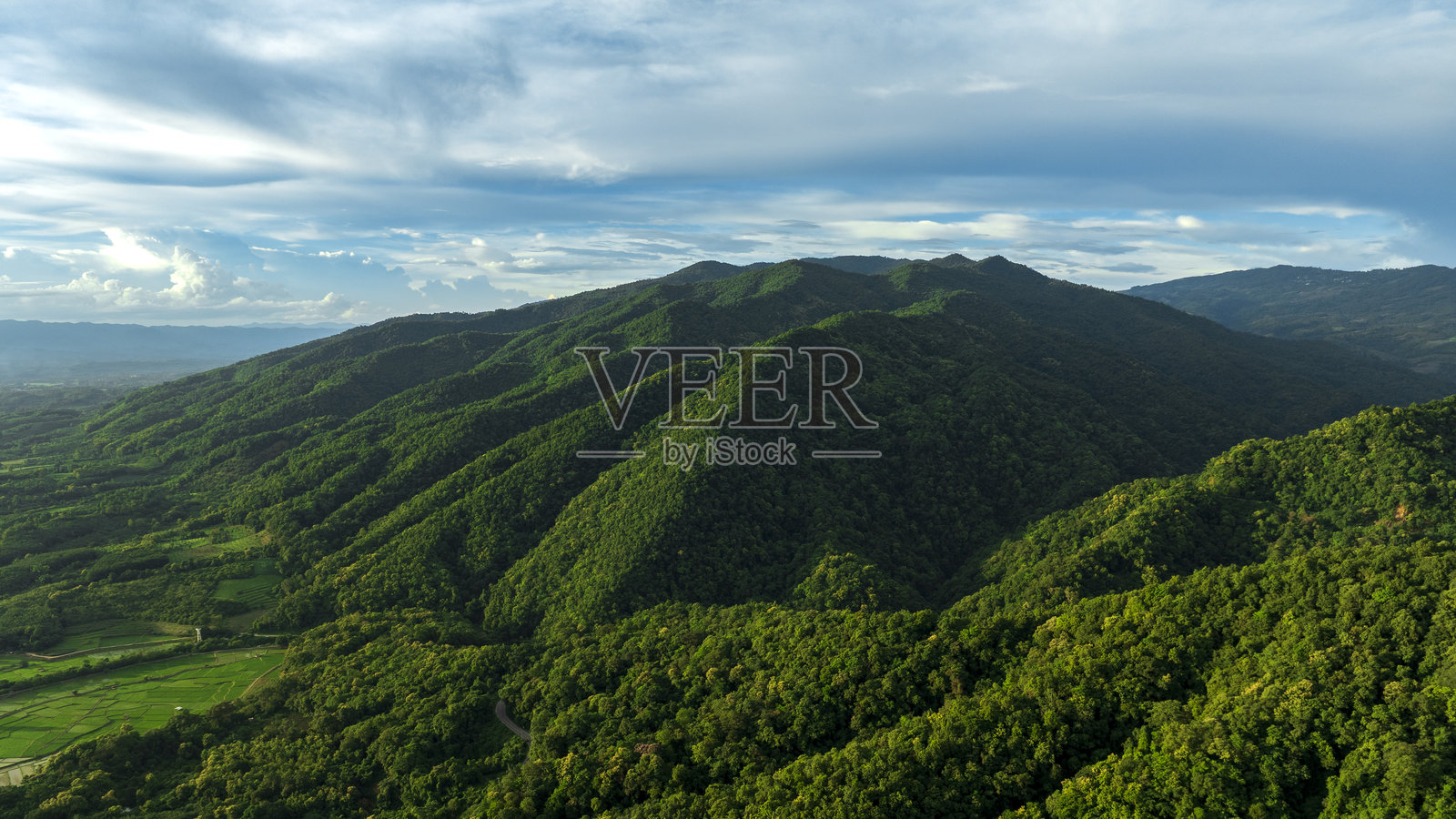蓝天之下，青山与美丽的云彩，绿草如茵的草地上盛开着野花。照片摄影图片